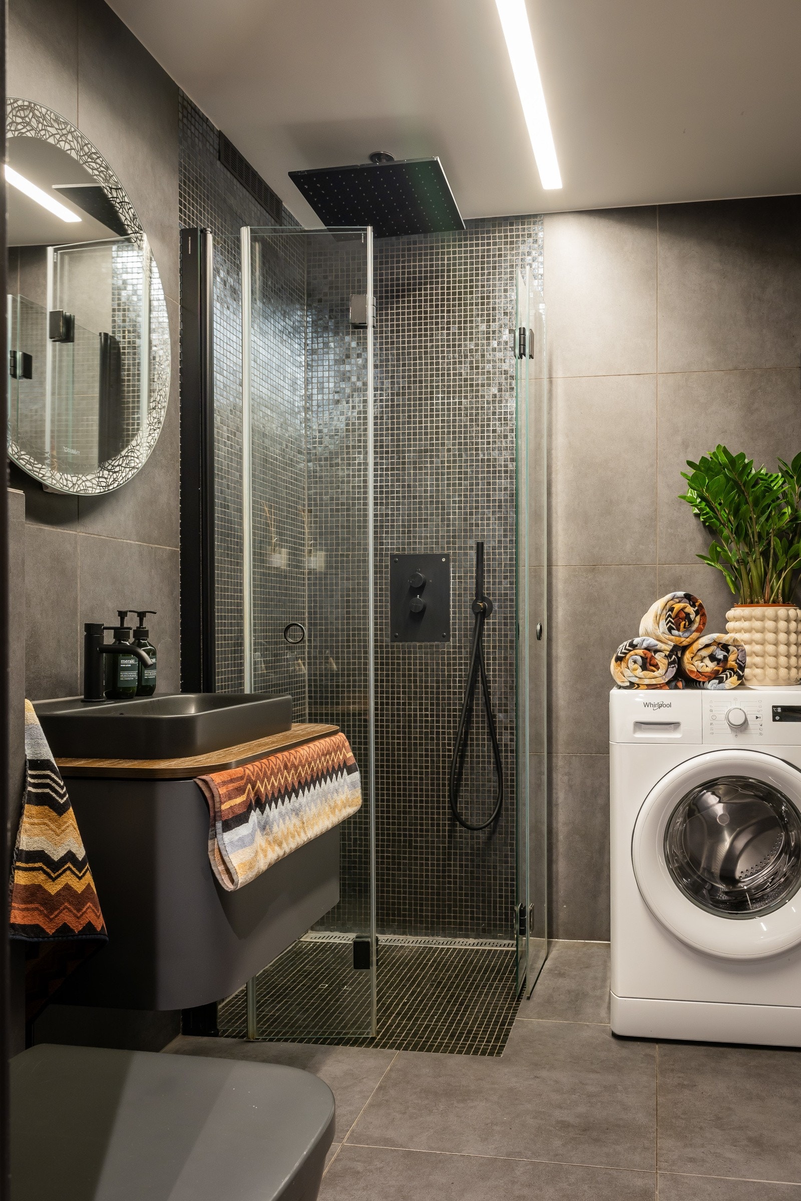 Pent flislagt baderom med varmekabler og belysning. Badet har servant med innredning, speil, dusjhjørne med nedsenk og innfellbare glassdører og vegghengt toalett. Galleribilde