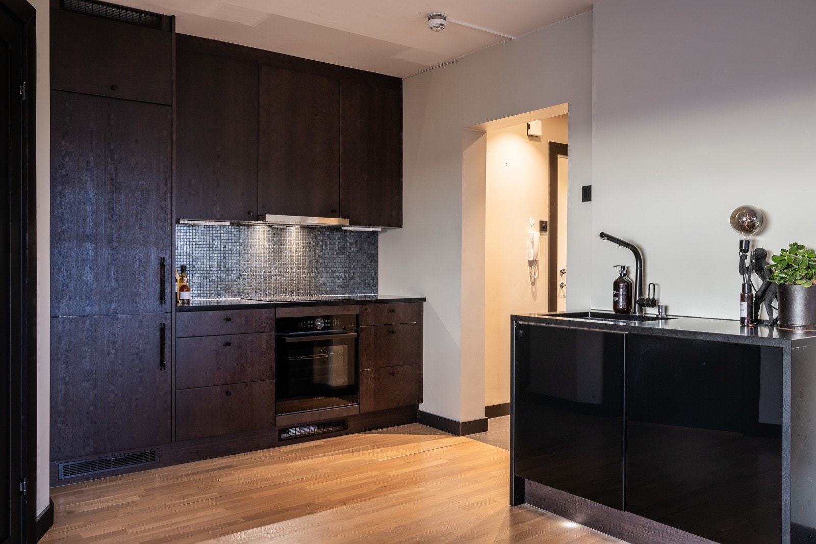 Videre er kjøkkenet utstyrt med nedfelt induksjonstopp, integrert komfyr, oppvaskmaskin og kjøl/frys Galleribilde