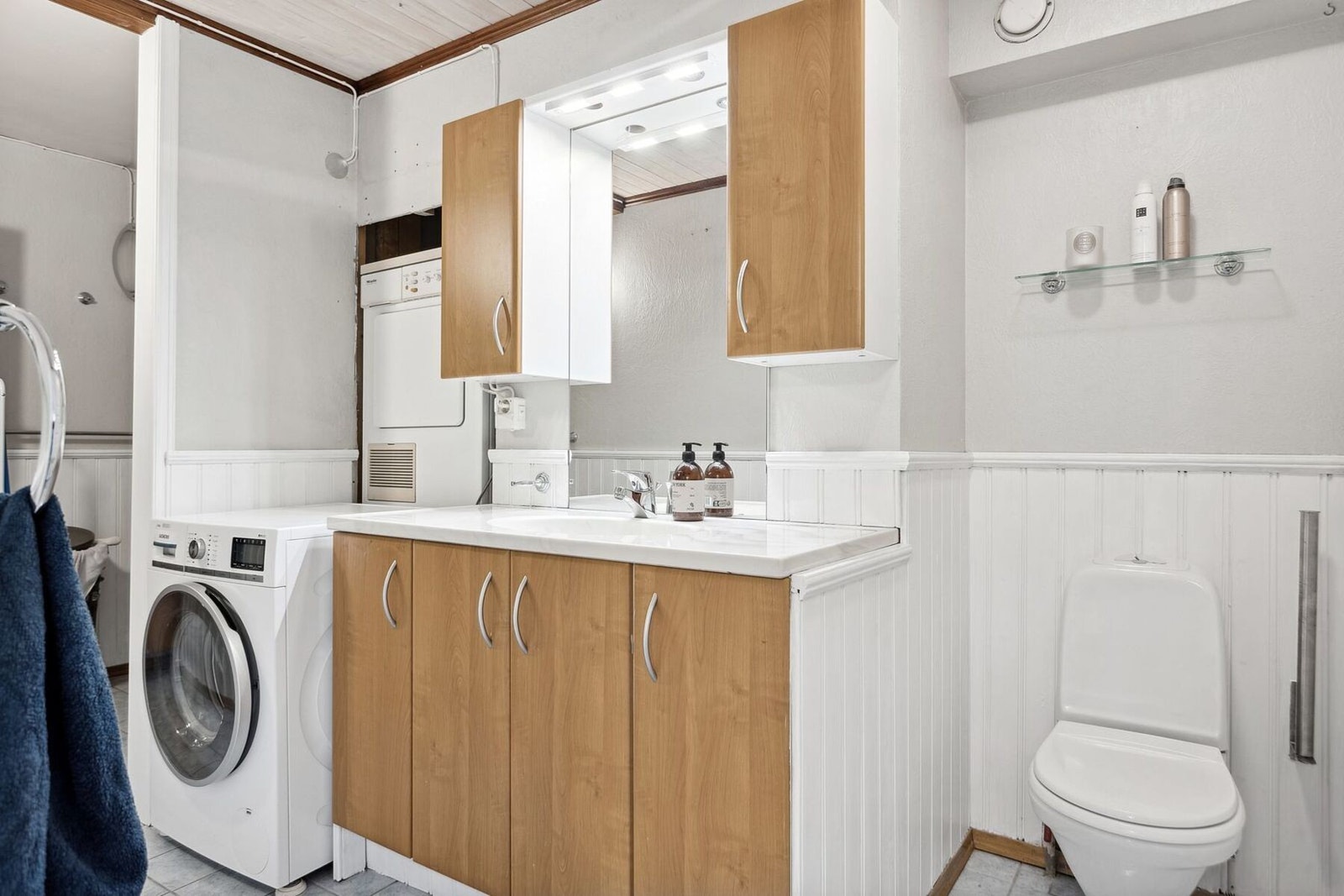 Badet er utstyrt med servant med innredning, dusjhjørne, gulvklosett, og opplegg for vaskemaskin/tørketrommel Galleribilde