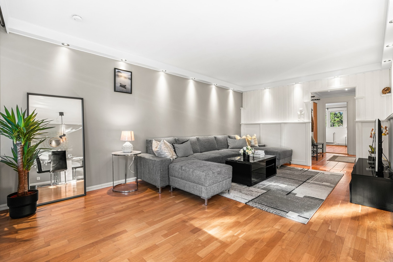 Stuen har lyst 2-stavs parkettgulv, nedfeldte lyskasser med downlights, lysmalte veggflater og noe panel. Galleribilde