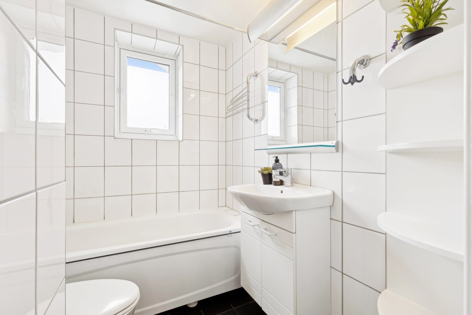 Flislagt baderom med varmekabler i gulv og malt himling. Badet ble pusset opp i regi av borettslaget i 2001/2002, og soilrør og sluk ble skiftet i den forbindelse. Galleribilde