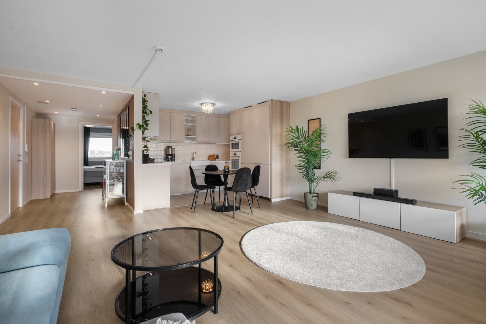 Utformingen av rommet gir god plass til en komfortabel sofa, tv-løsning og et spisebord som får naturlig plass i grensen ved kjøkkenet Galleribilde