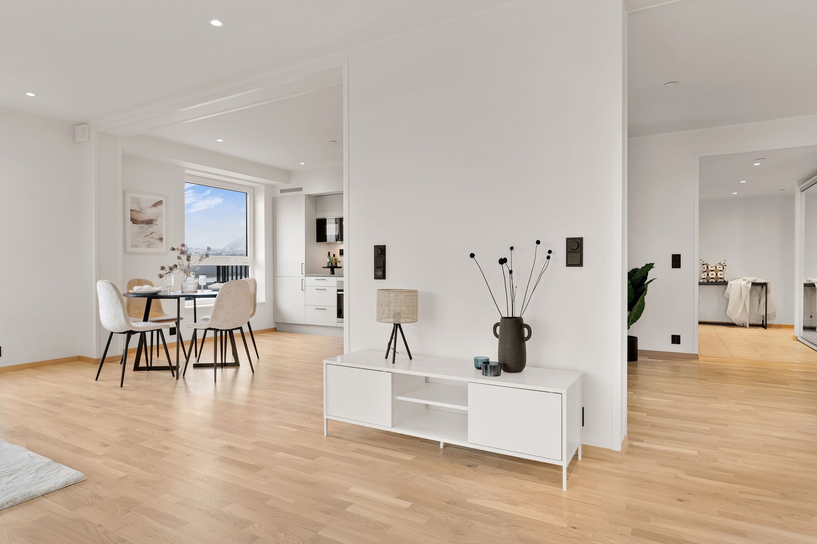 Åpen løsning mellom stue og kjøkken med en skillevegg som skaper en naturlig adskillelse av sonene. Galleribilde