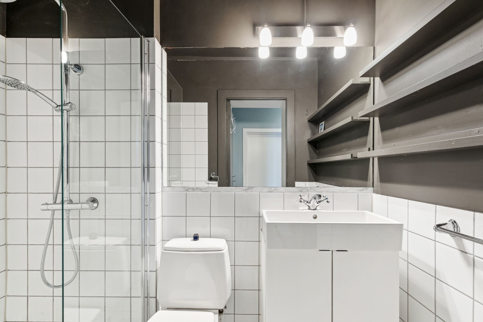 Stilrent bad med wc, baderomsinnredning med heldekkende servant, stort speil og dusjnisje. Galleribilde