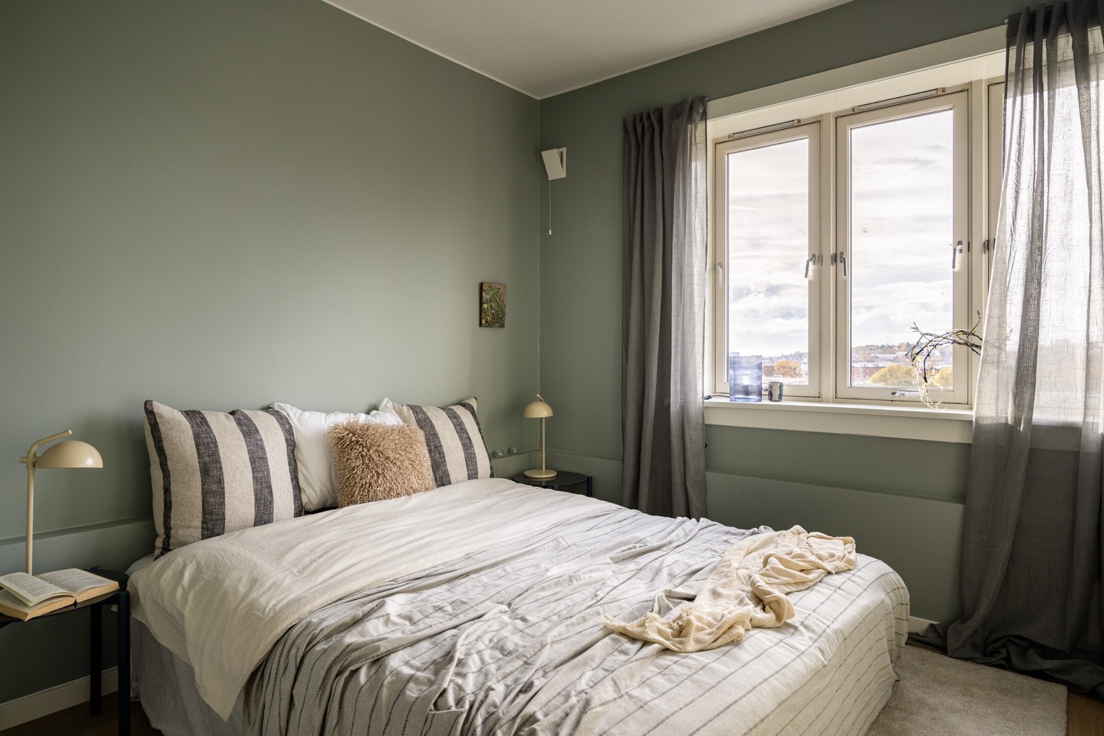 Soverommet er lyst og innbydende, med en tidløs fargepalett som skaper en rolig atmosfære. De grønne veggene gir en behagelig og harmonisk følelse, og rommet har store vindusflater som slipper inn rikelig med naturlig lys. Galleribilde