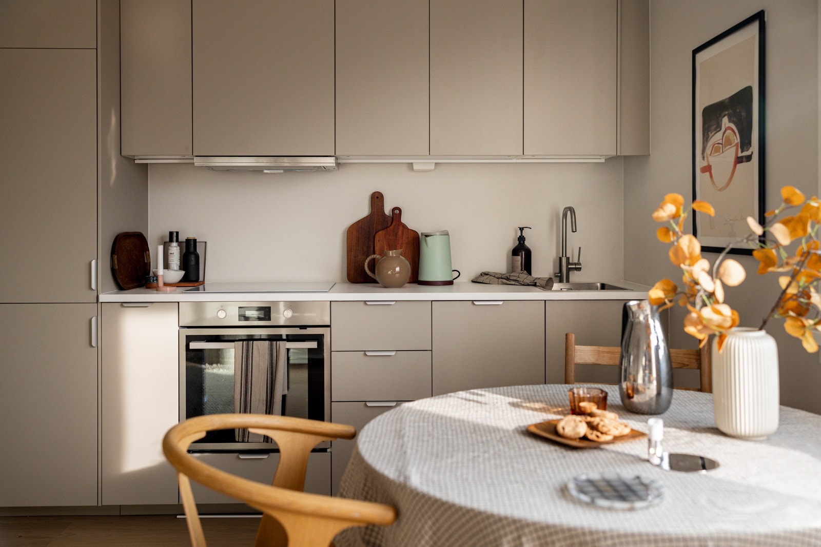 Stilren og funksjonell kjøkkeninnredning fra 2024. Innredningen består av lyse, glatte fronter og en laminat benkeplate med nedfelt kum i rustfritt stål. Galleribilde