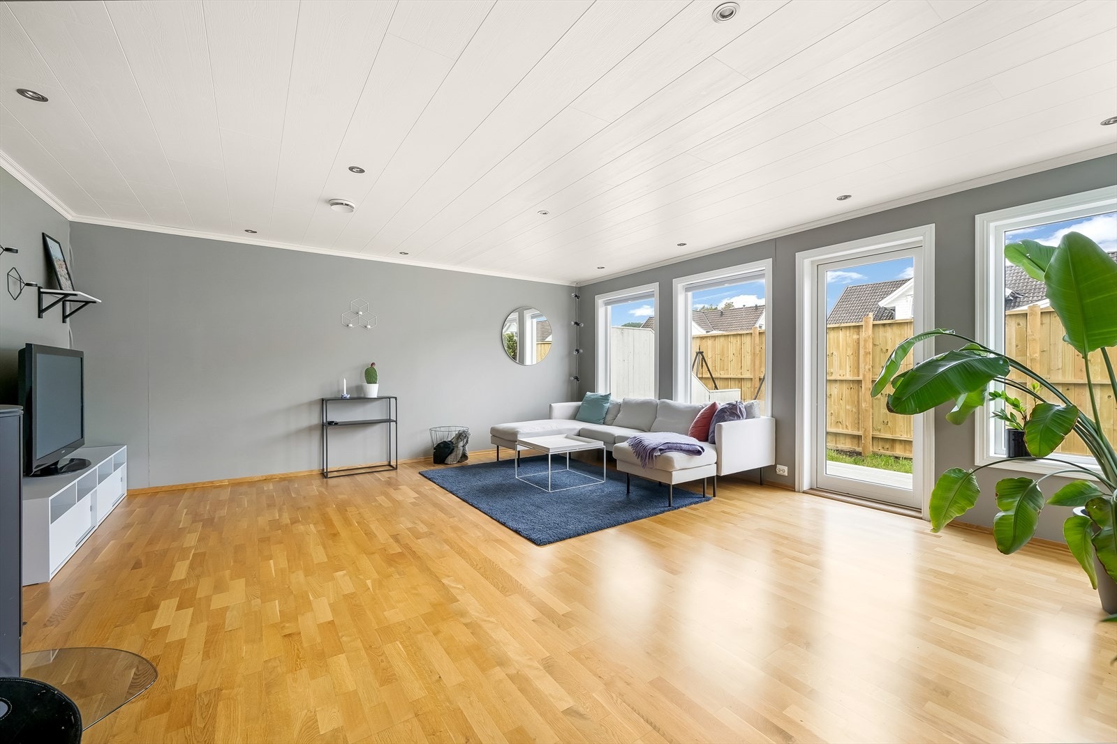 Gjennom de store vindusflatene i stua får man godt med lys inn. Utgang til en usjenert uteplass på baksiden av boligen. Galleribilde