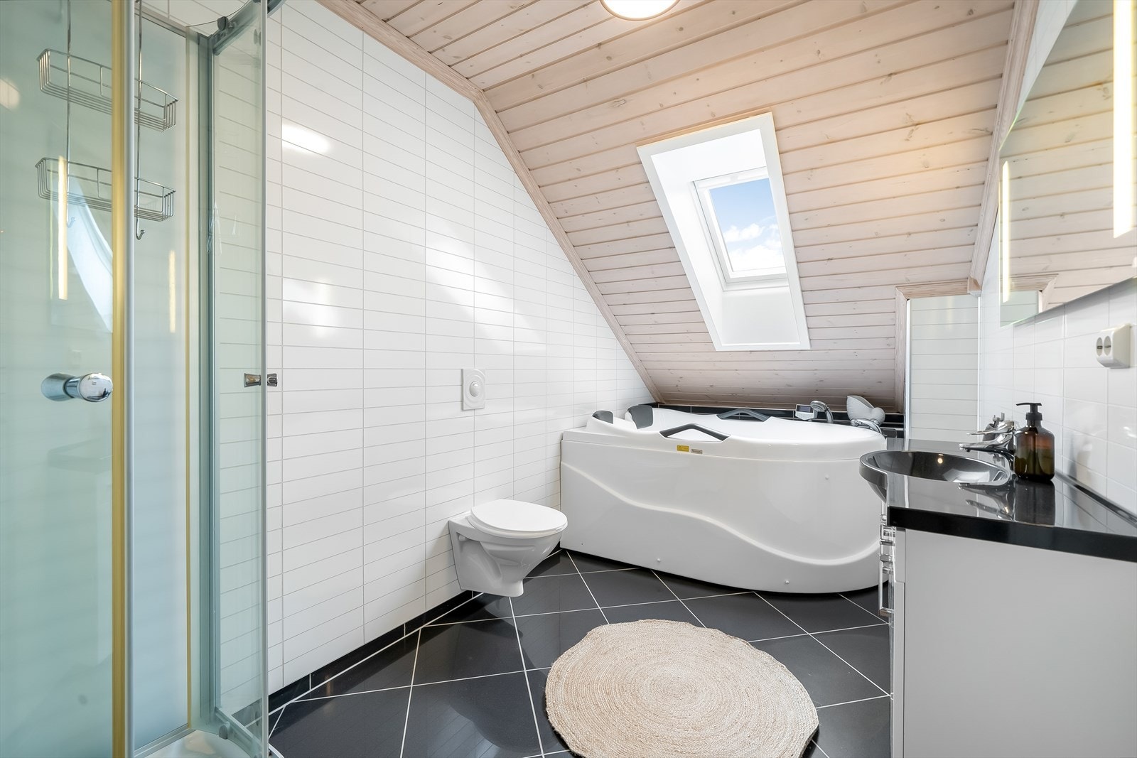 Stort bad i 2. etasje med fliser med varmekabler på gulv og baderomsplater på vegg. Rommet er innredet med baderomsinnredning, toalett, dusjkabinett og boblebad. Galleribilde