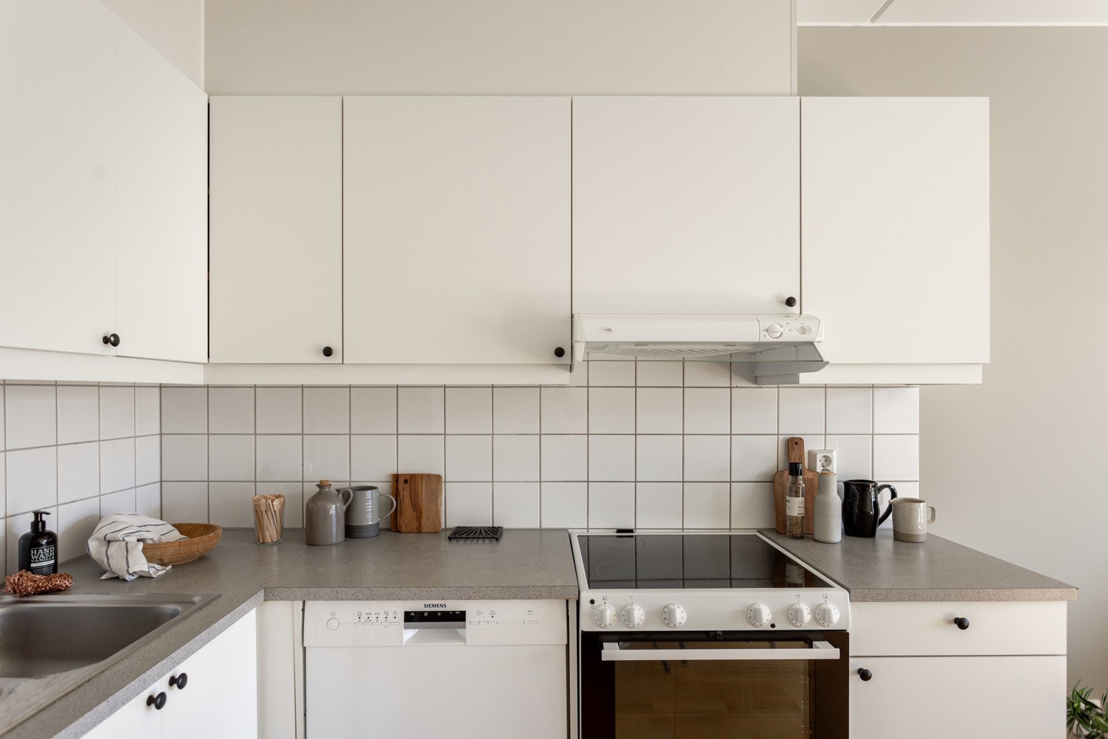 Lys og tidløs kjøkkeninnredning med god skap- og benkeplass. Innredningen har hvite glatte fronter og laminert benkeplate med nedfelt oppvaskkum. Praktisk med lyse fliser i benkeryggen og belysning under overskapene. Galleribilde