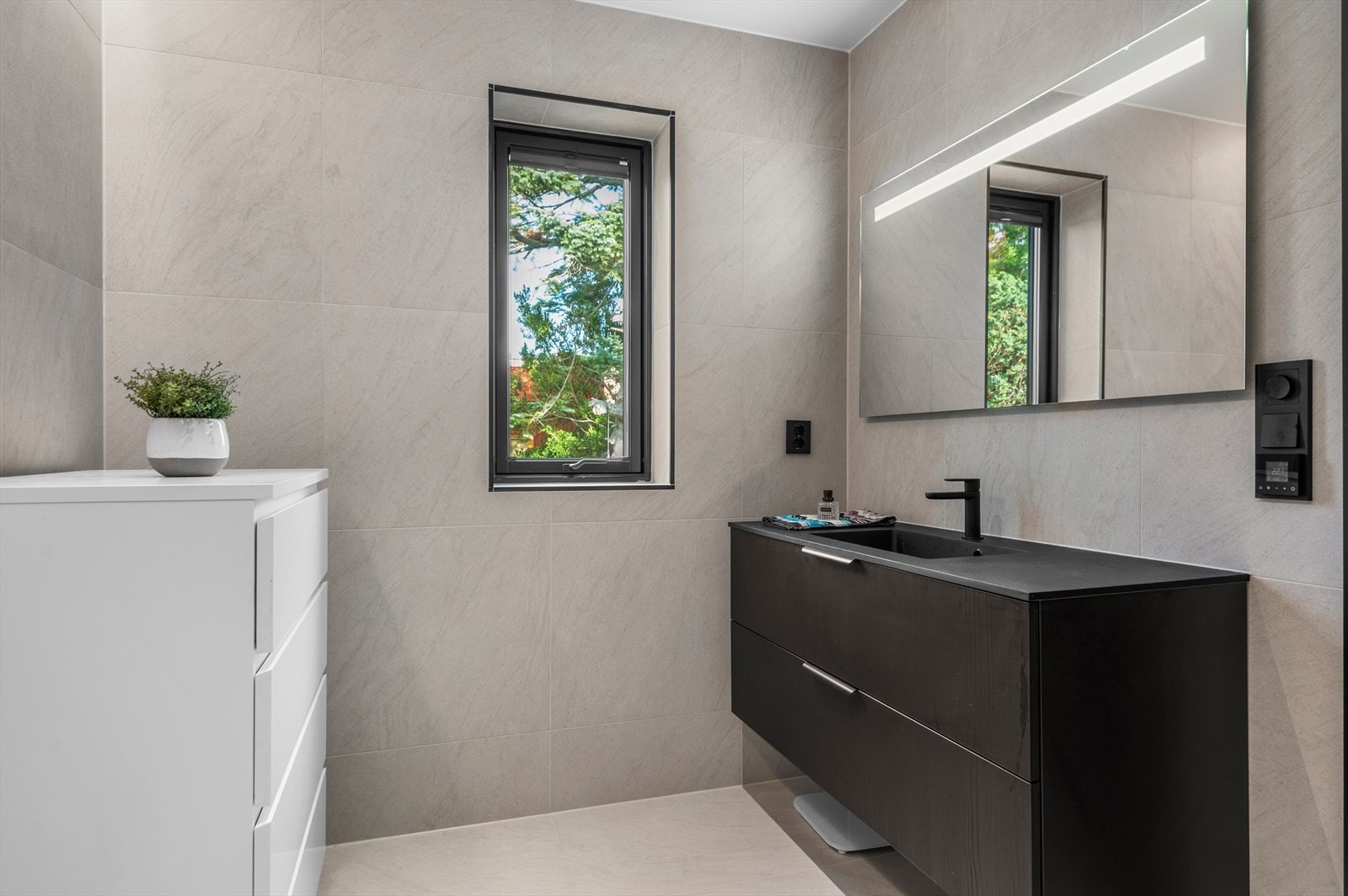 Badet er på romslige 7m² med behagelig gulvvarme. Det er flis på vegger og malt slett innvendig tak med spotter og lysstripe Galleribilde