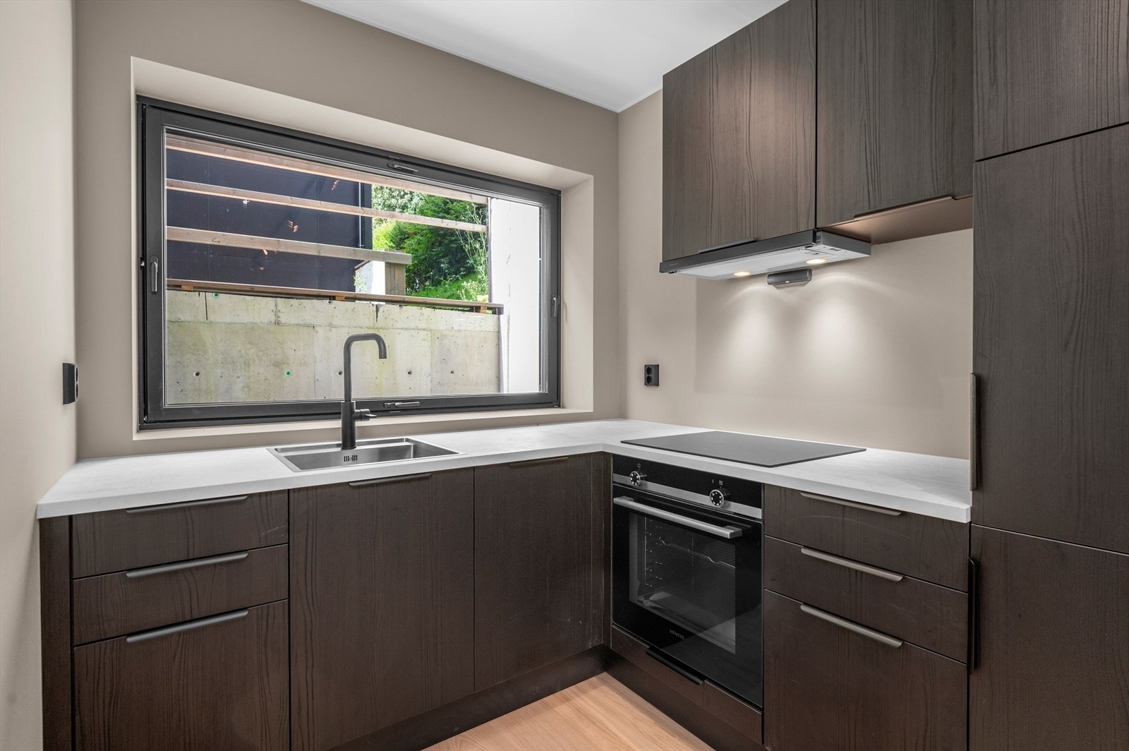 Kjøkkenet er innredet med laminert glatte fronter og laminat benkeplate med nedfelt induksjonstopp, nedfelt oppvaskkum og 1-greps blandebatteri. Videre er det integrerte hvitevarer som frys/kjøleskap, stekeovn og oppvaskmaskin Galleribilde