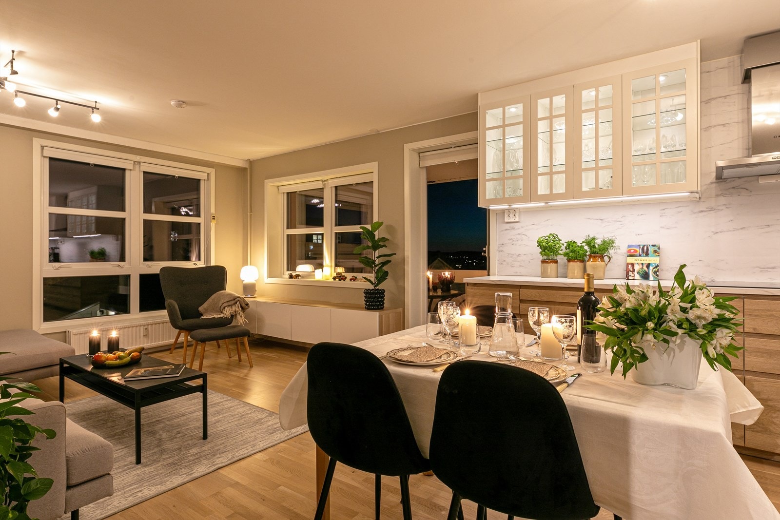 Åpen planløsning mellom stue og kjøkken som gjør det stemningsfullt mot kvelden Galleribilde