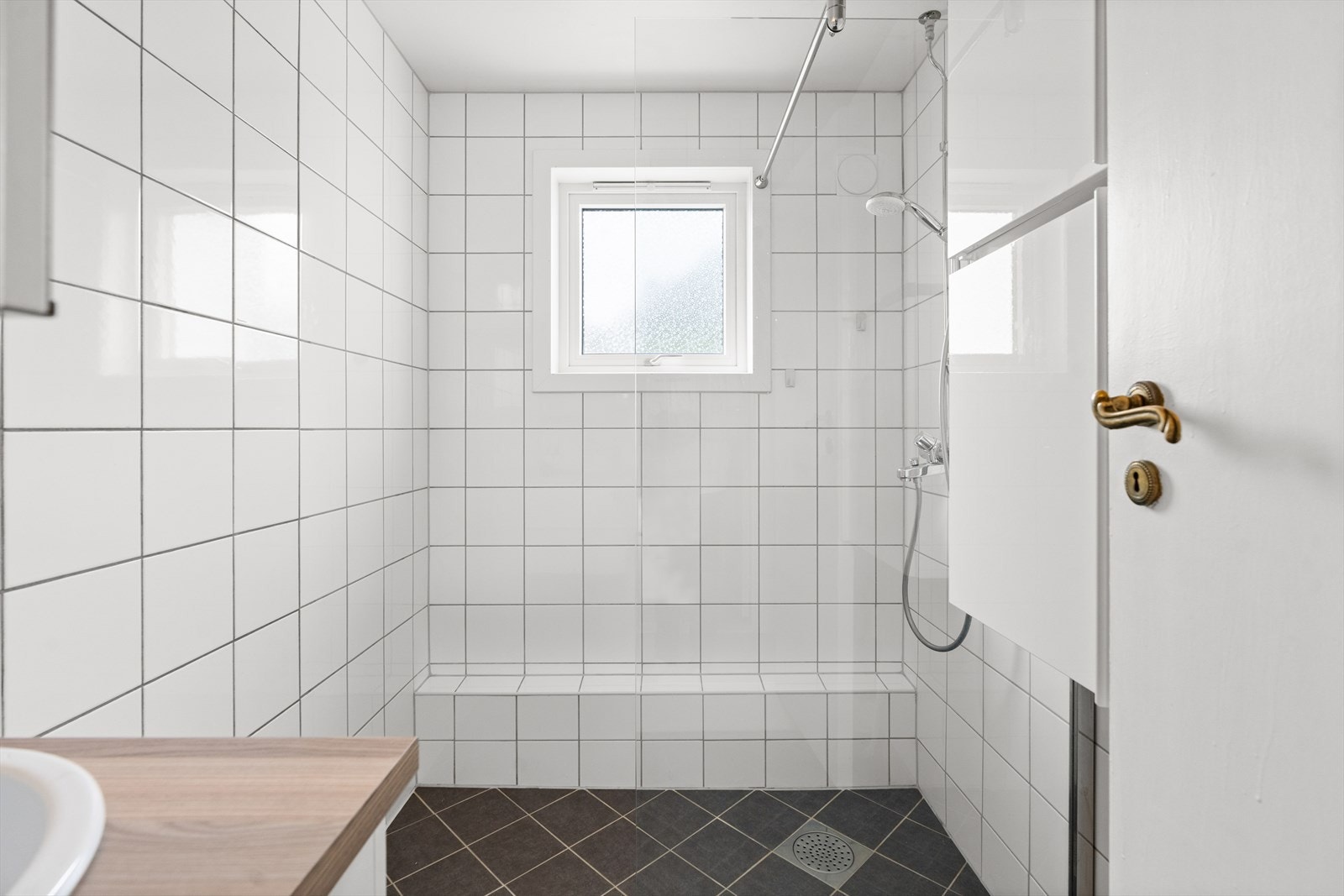 Rommet er innredet med servant nedfelt i innredning og dusjhjørne med glassvegg. Det er naturlig avtrekk. Galleribilde