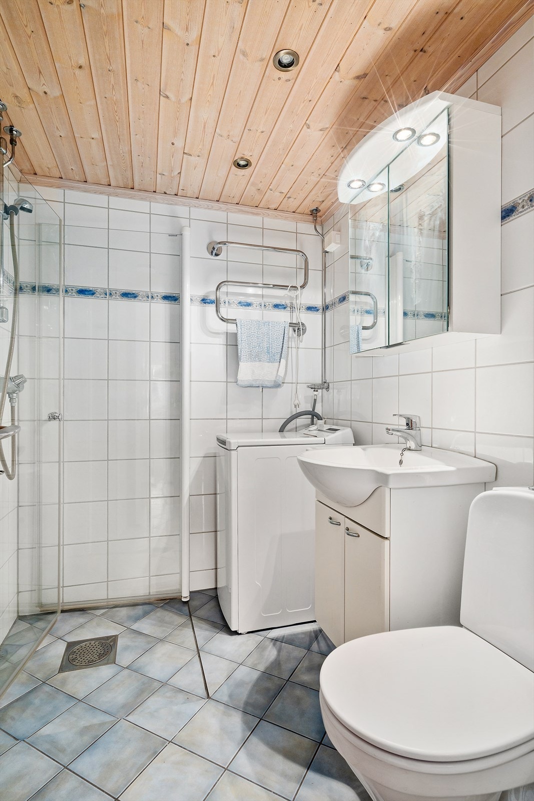 Badet har innredning med nedfelt servant, toalett, dusjvegger/hjørne og opplegg for vaskemaskin. Galleribilde