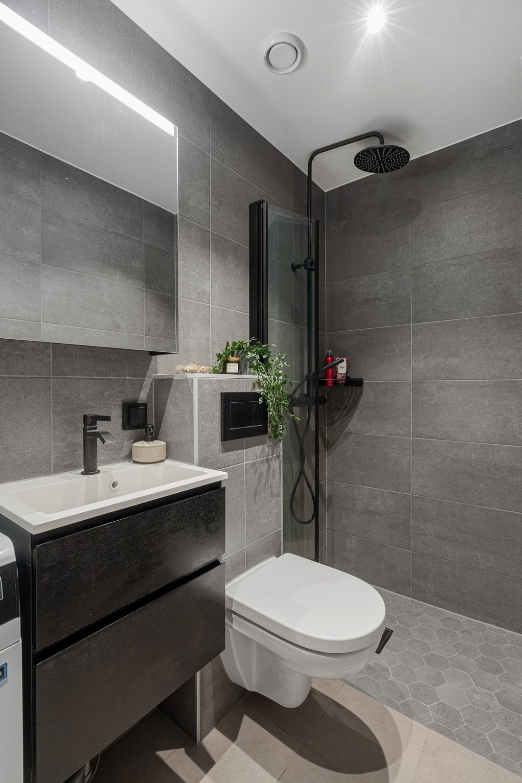 Badet har overflater med fliser, behagelig gulvvarme og downlights i himling. Det er opplegg for vaskemaskin. Galleribilde