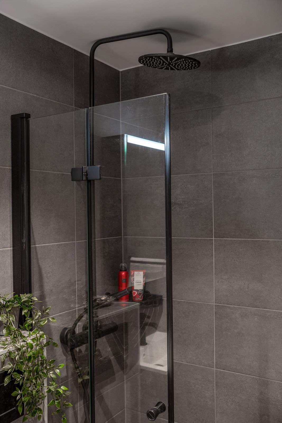 Rommet inneholder dusjhjørne med innfellbare dusjdører, veggmontert toalett og baderomsinnredning med skuffer, servant og speilskap. Galleribilde