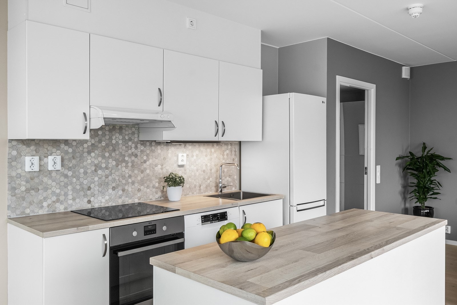 Kjøkkenøy med tilsvarende komponenter som kjøkkeninnredning - Stekeovn og platetopp er integrert i innredningen samt opplegg for oppvaskmaskin Galleribilde