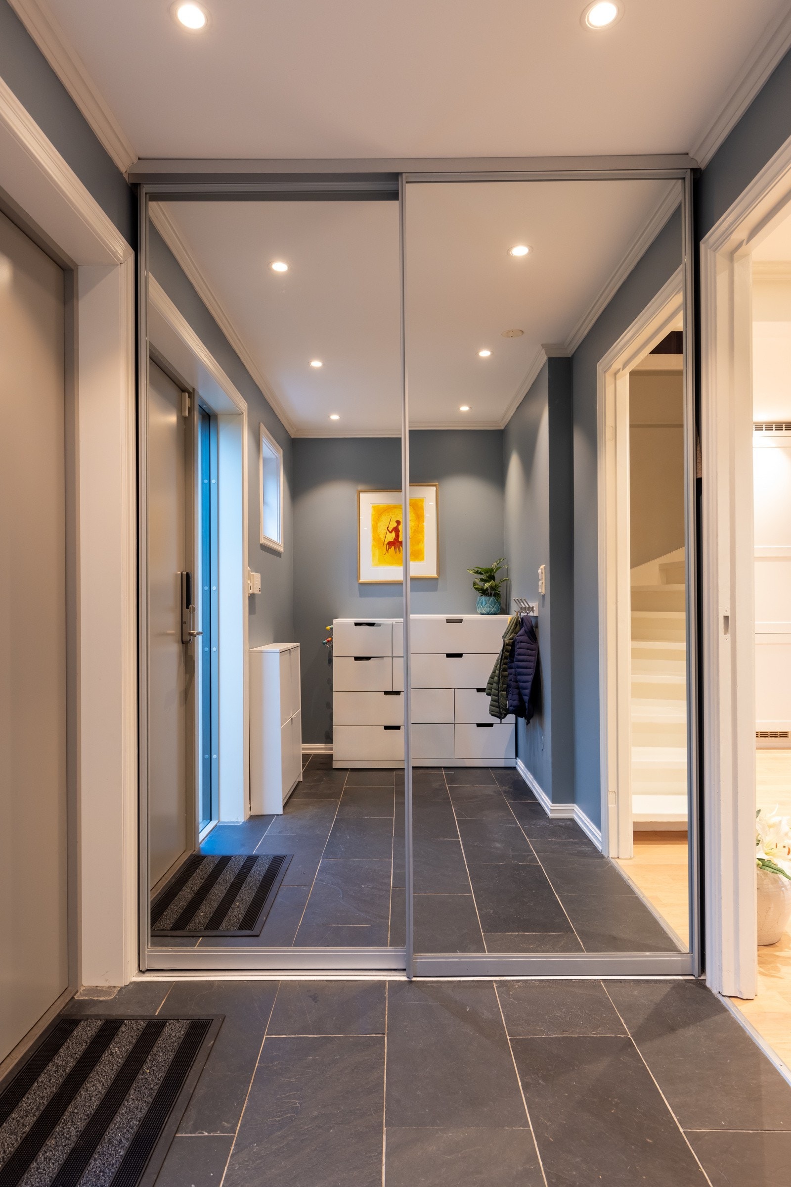 Innbydende entré med flislagt gulv med varmekabler og god oppbevaringsplass i skyvedørsgarderobe med speildører. Galleribilde