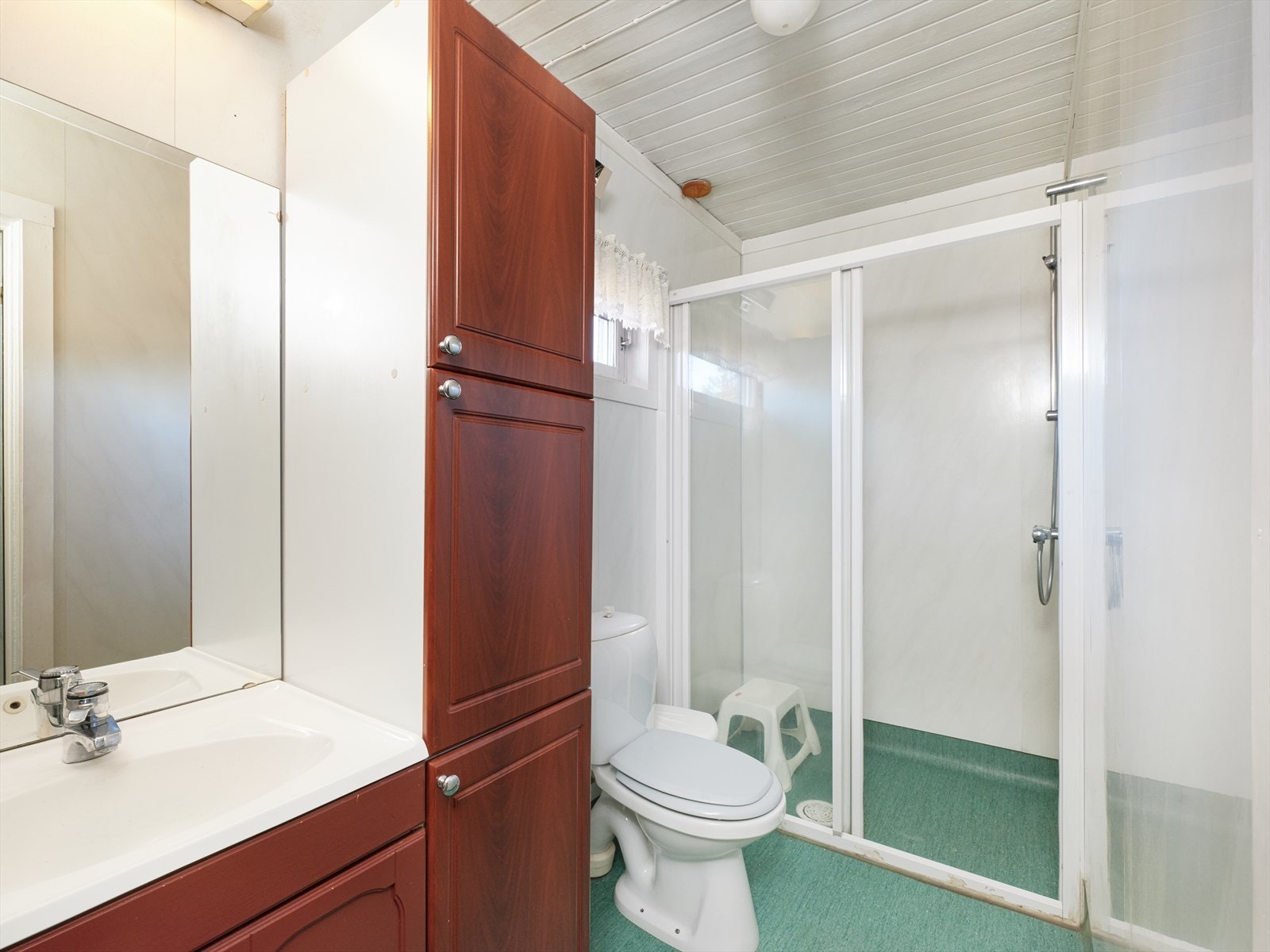 Bad i 1.etasje innredet med toalett, servant på innredning og dusjhjørne. Galleribilde