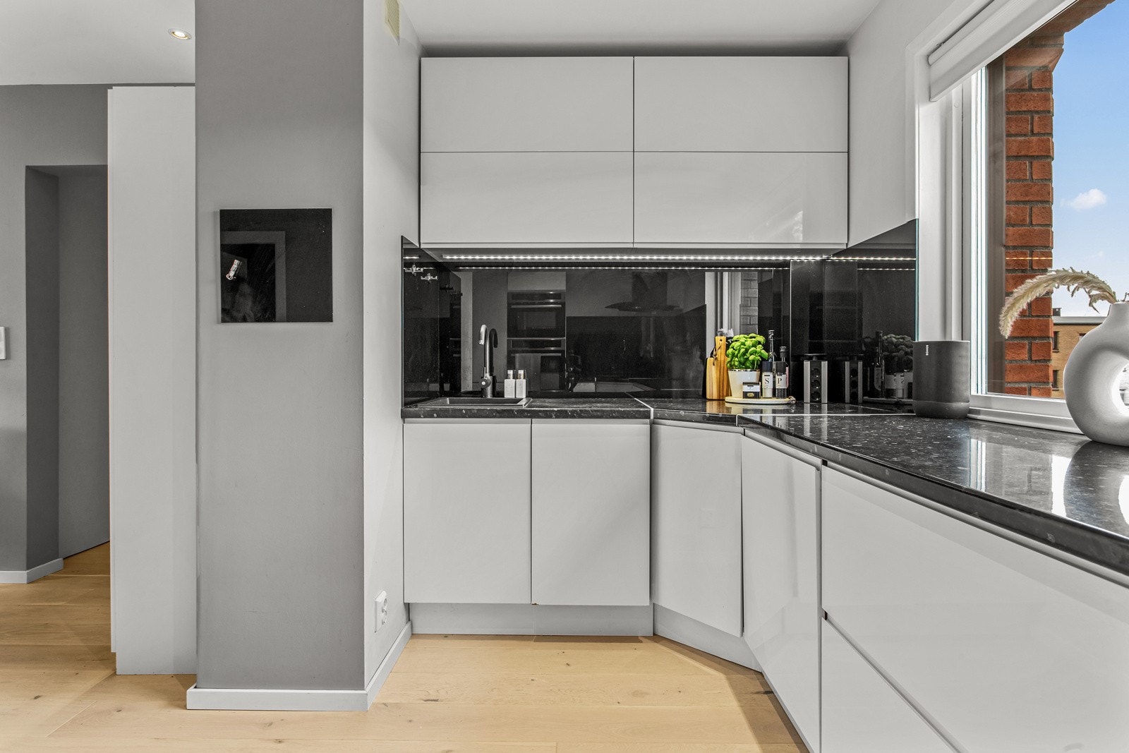 Kjøkkeninnredning med lyse, glatte fronter og benkeplate i laminat. Galleribilde