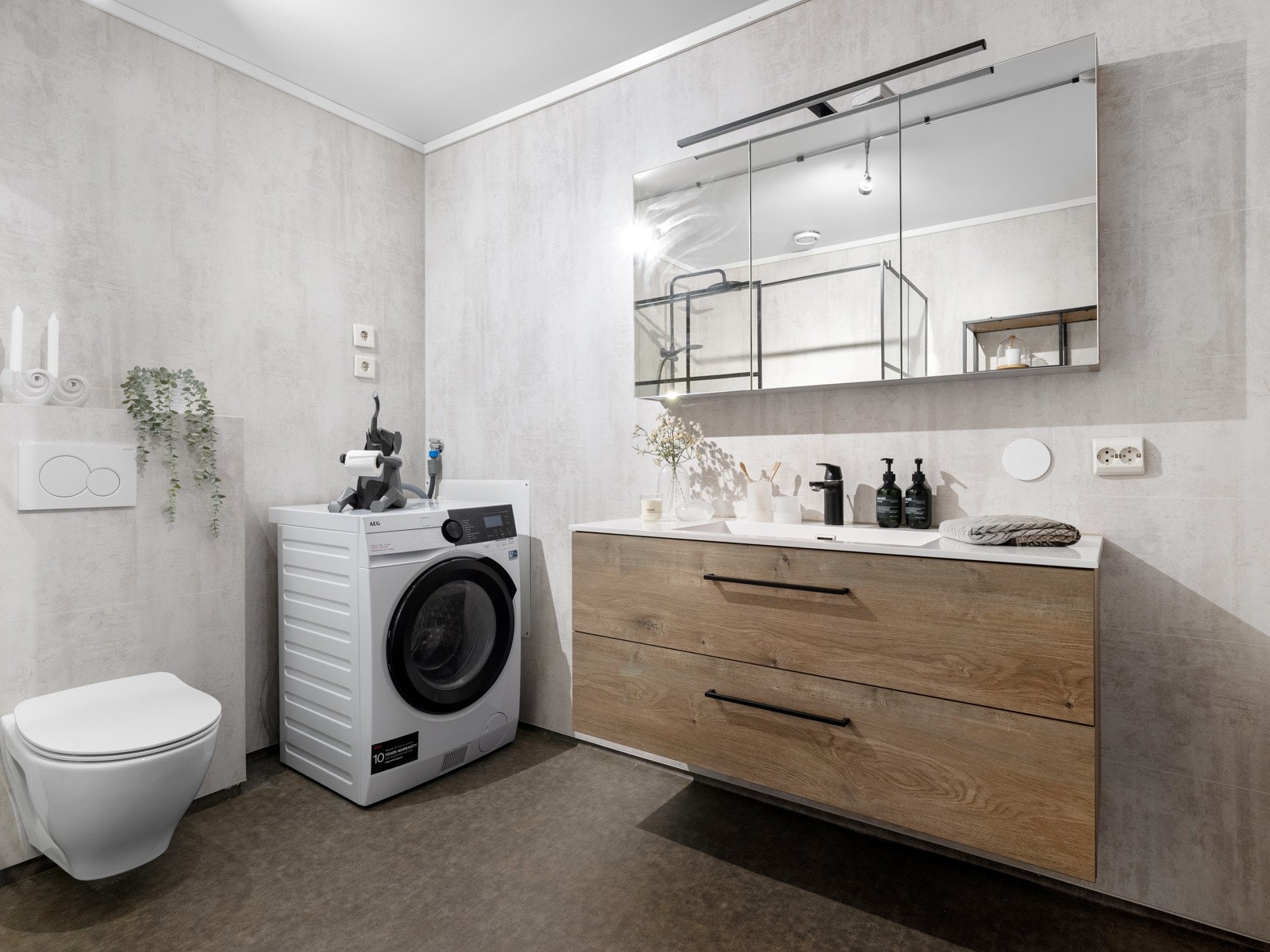 Det vegghengte toalettet og dusjhjørnet med glassvegger og moderne svarte detaljer gir et stilrent uttrykk. Badet er også utstyrt med opplegg for både vaskemaskin og tørketrommel. Galleribilde