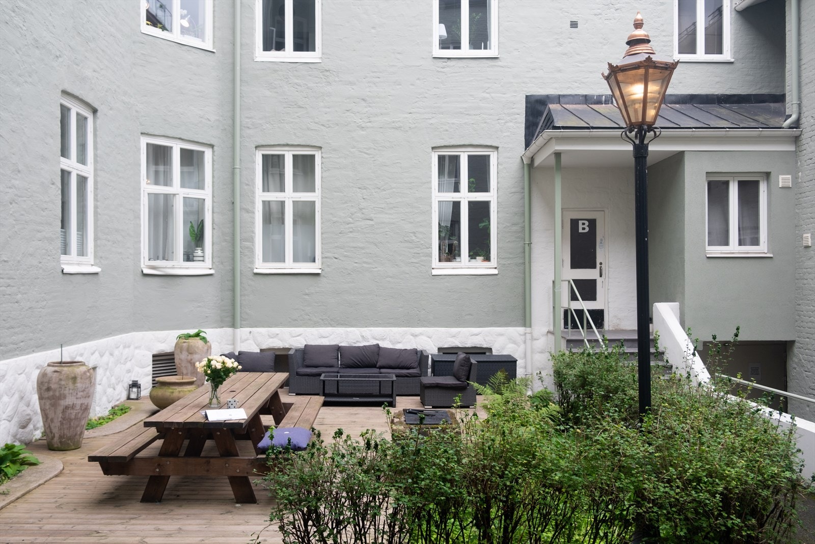 Bakgården har flere sittegrupper og frodig beplantning Galleribilde