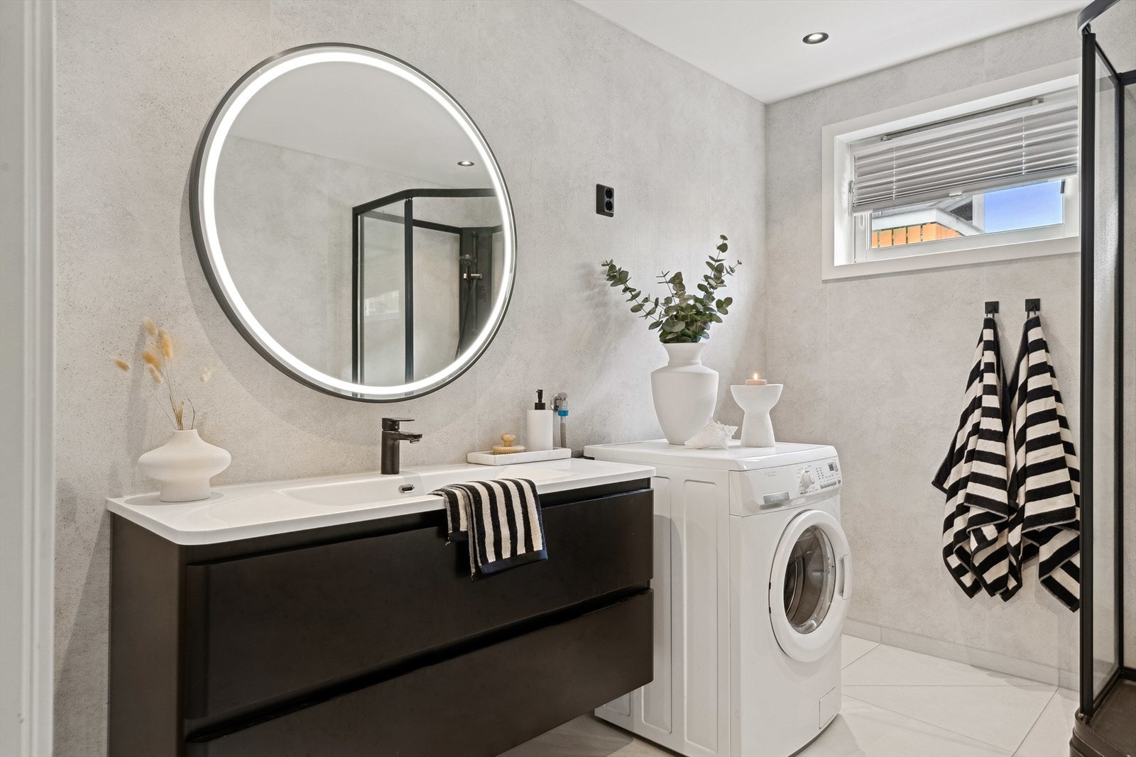 Baderommet bærer preg av delikate farge- og materialvalg, med sorte detaljer og speil med belysning. Galleribilde