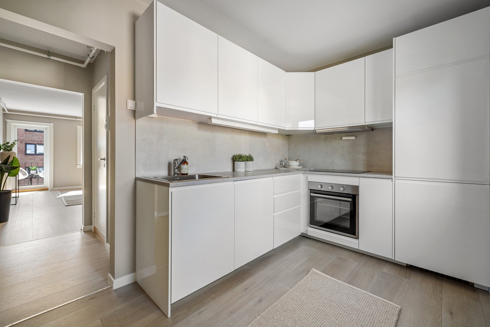 Moderne kjøkken med glatt innredning fra Ikea, soft close, laminat benkeplate med nedfelt stålkum og induksjonstopp, integrert komfyr, oppvaskmaskin, kjøl/frys. Galleribilde