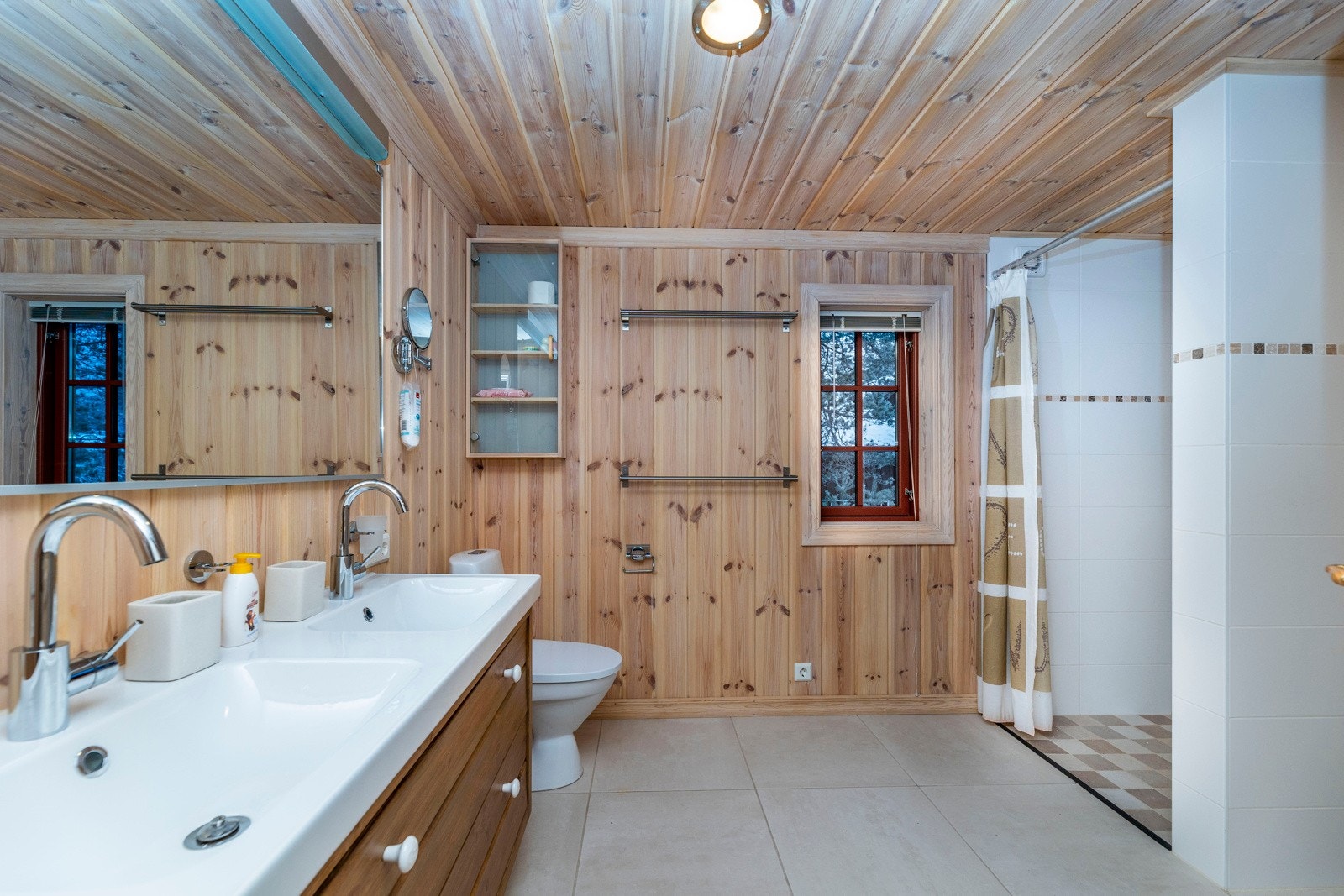 Romslig baderom innredet med dusj, klosset og servant med underskaper. Galleribilde