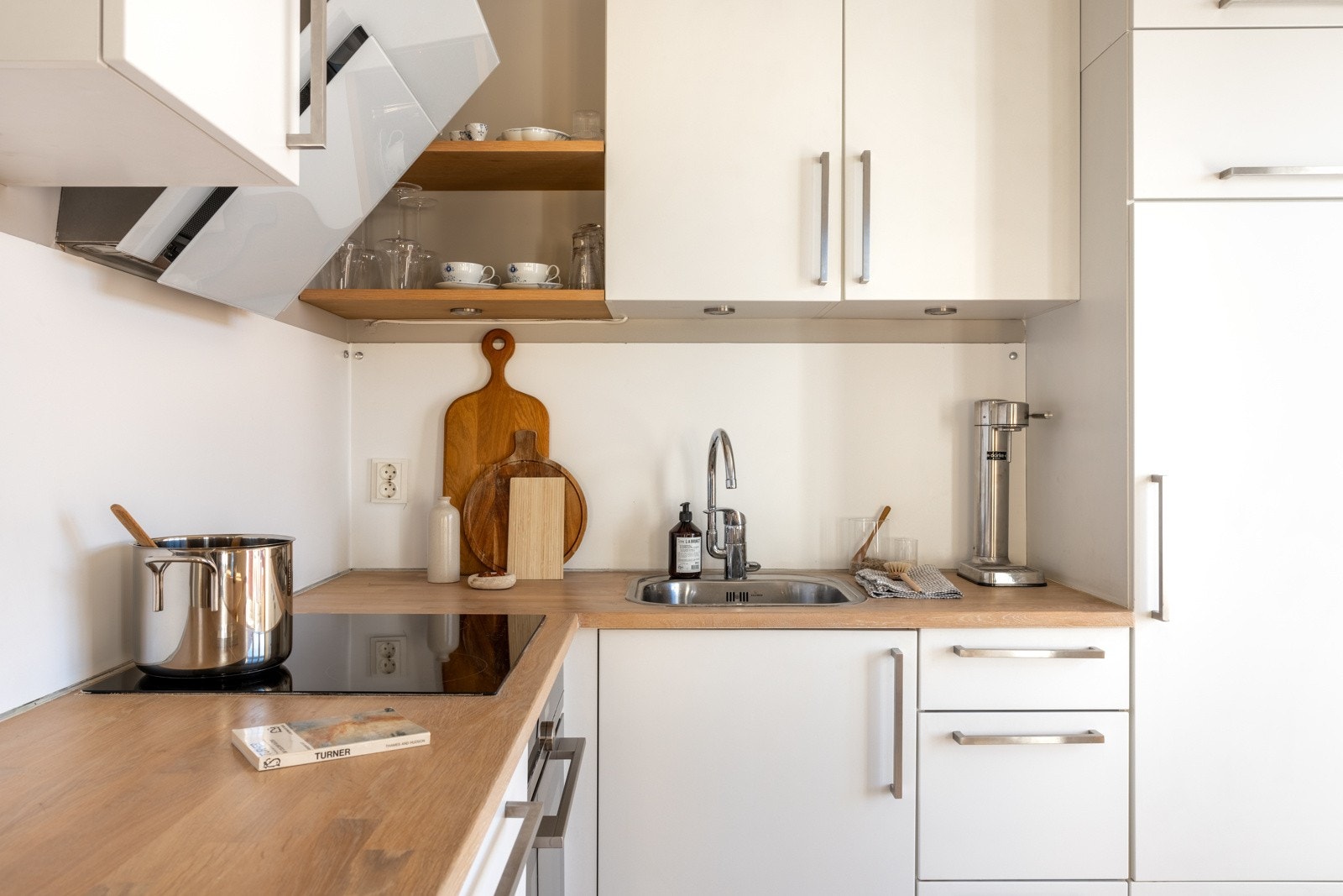 Kjøkkeninnredningen er fra IKEA og består av slette hvite fronter og en heltre benkeplate med nedfelt vask av stål. Galleribilde