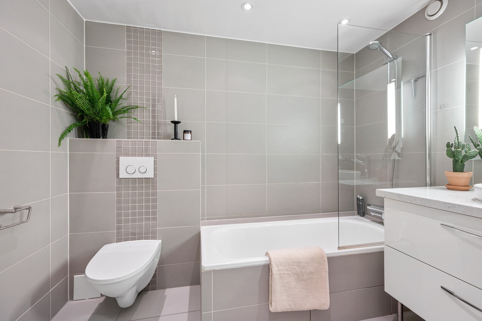 Badet fremstår moderne med veggmontert toalett, fin innredning, gulvvarme, downlights og opplegg for vaskemaskin. Galleribilde