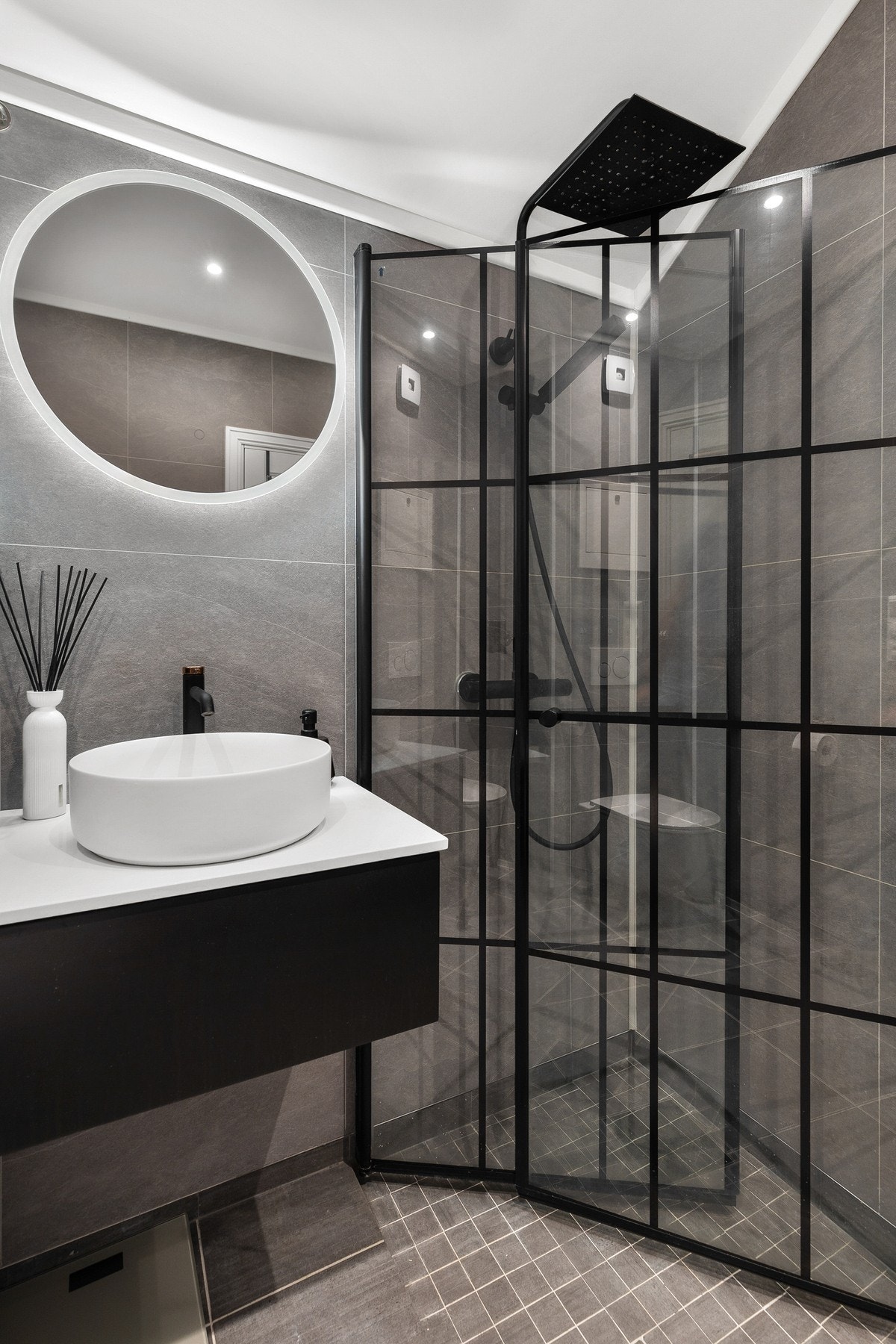 Rommet er innredet med vegghengt servantinnredning, speil, dusjhjørne med regndusj og vegghengt toalett Galleribilde