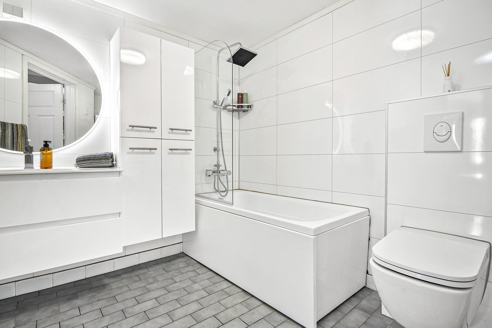 Innredningen på badet er bestående av servant med underskap, to høyskap, speil med integrert belysning, badekar med dusj og svingbar glassdør, veggmontert toalett med innebygget sisterne og opplegg for vaskemaskin. Galleribilde