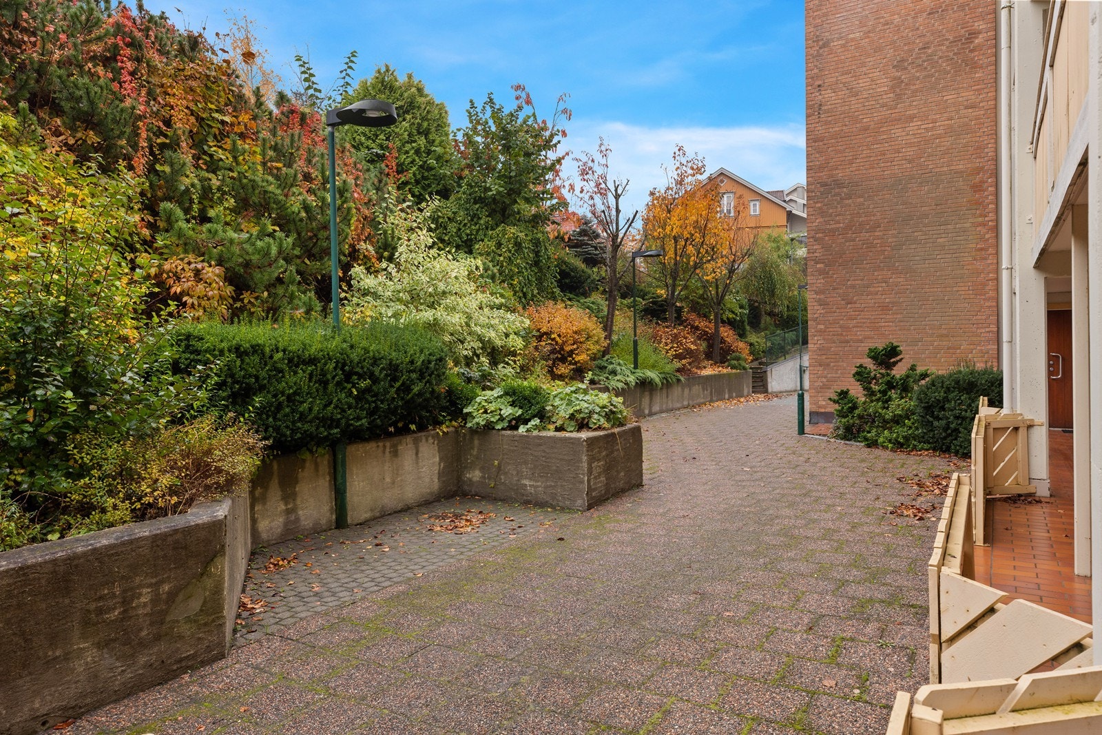 Tomten består hovedssakelig av bebyggelse. Fellesområder med sittegrupper. Det er etablert noe beplantning med blomster, busker m.m. Deler av innkjøring til bakside har belegningsstein og forøvrig steinheller. Galleribilde