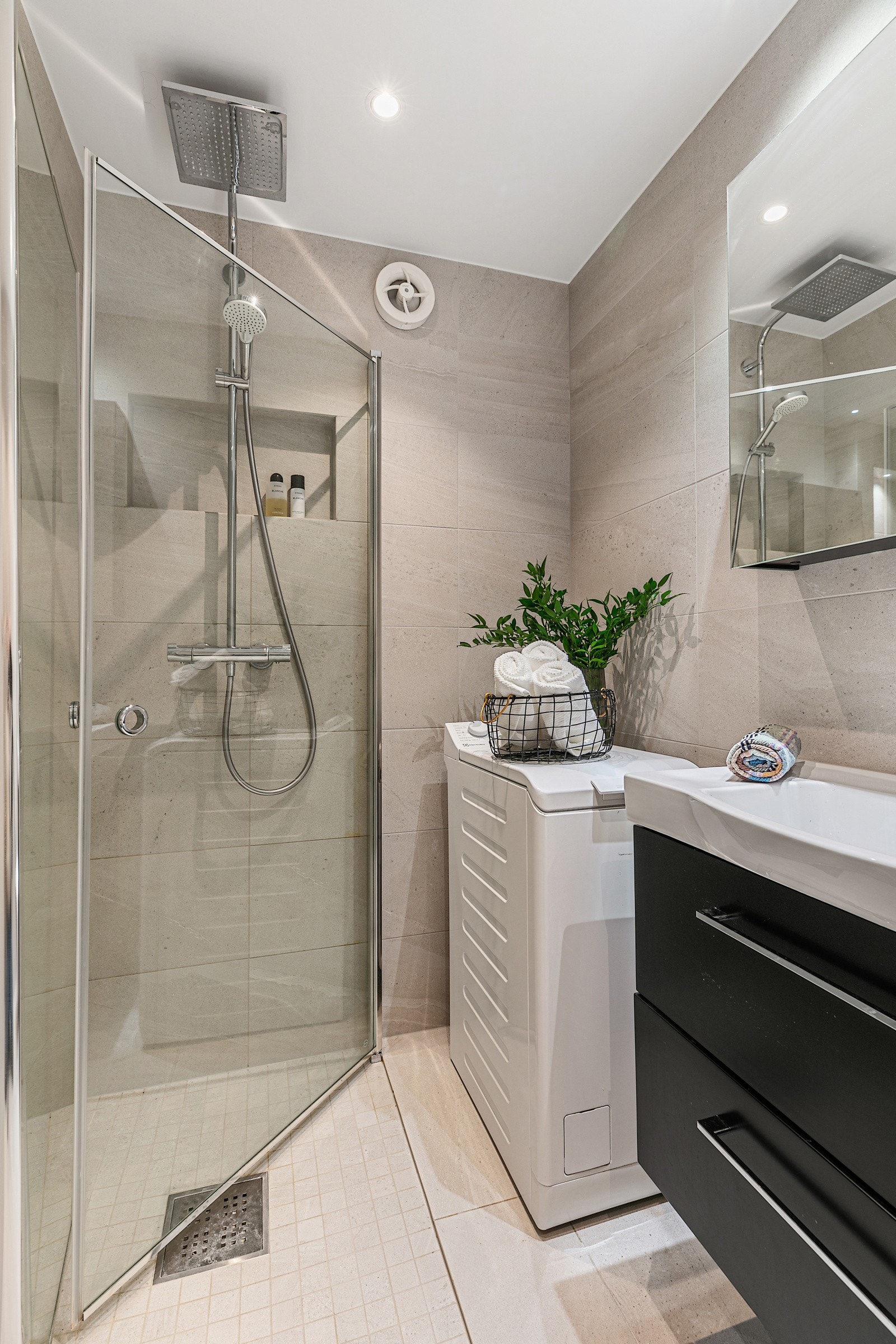Badet har innredning med servant, toalett, dusjplass med glassvegger, samt opplegg for vaskemaskin Galleribilde