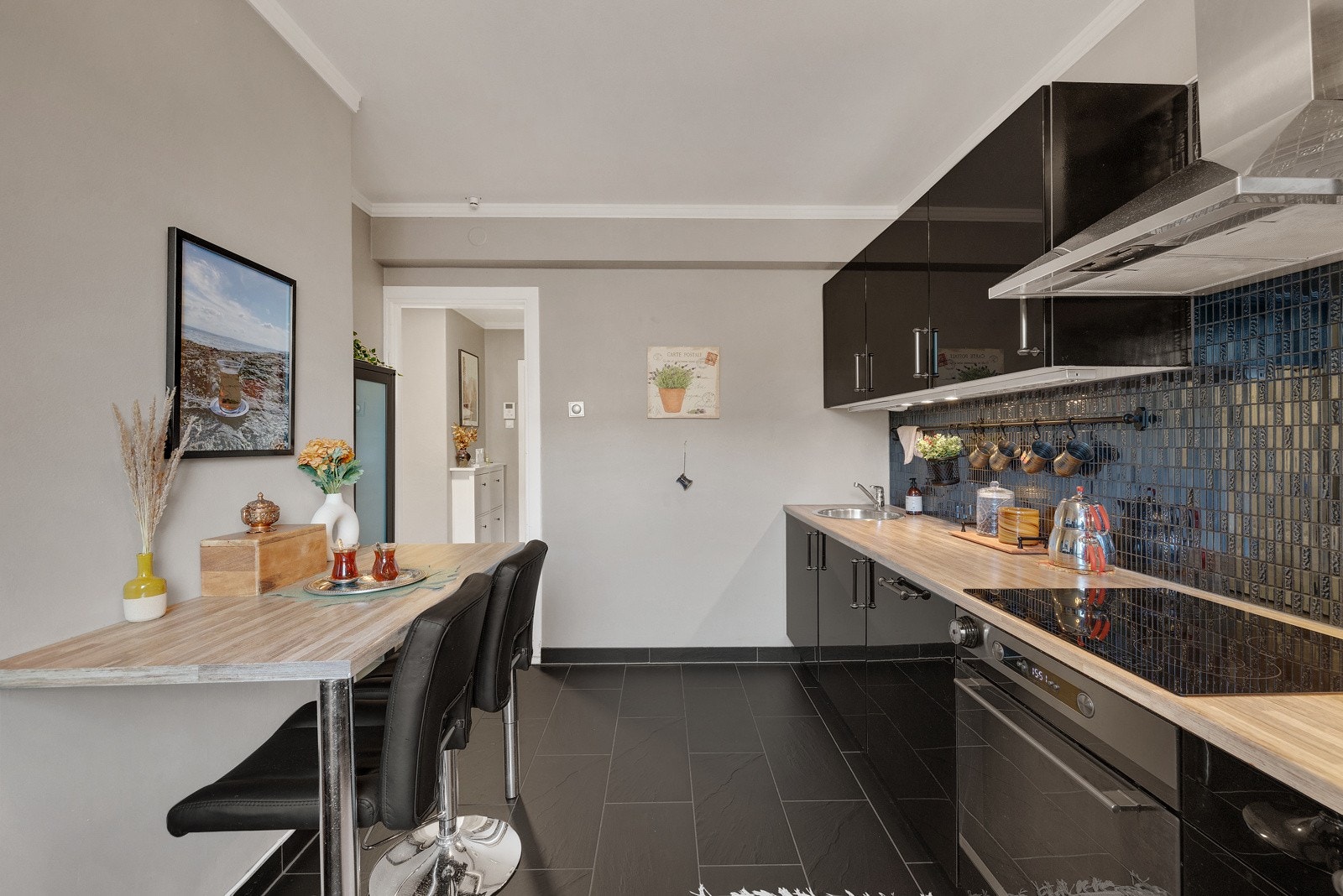 Tidsriktig og pent kjøkken med sorte, glatte fronter og laminert benkeplate med integrert kjøkkenkum. Galleribilde