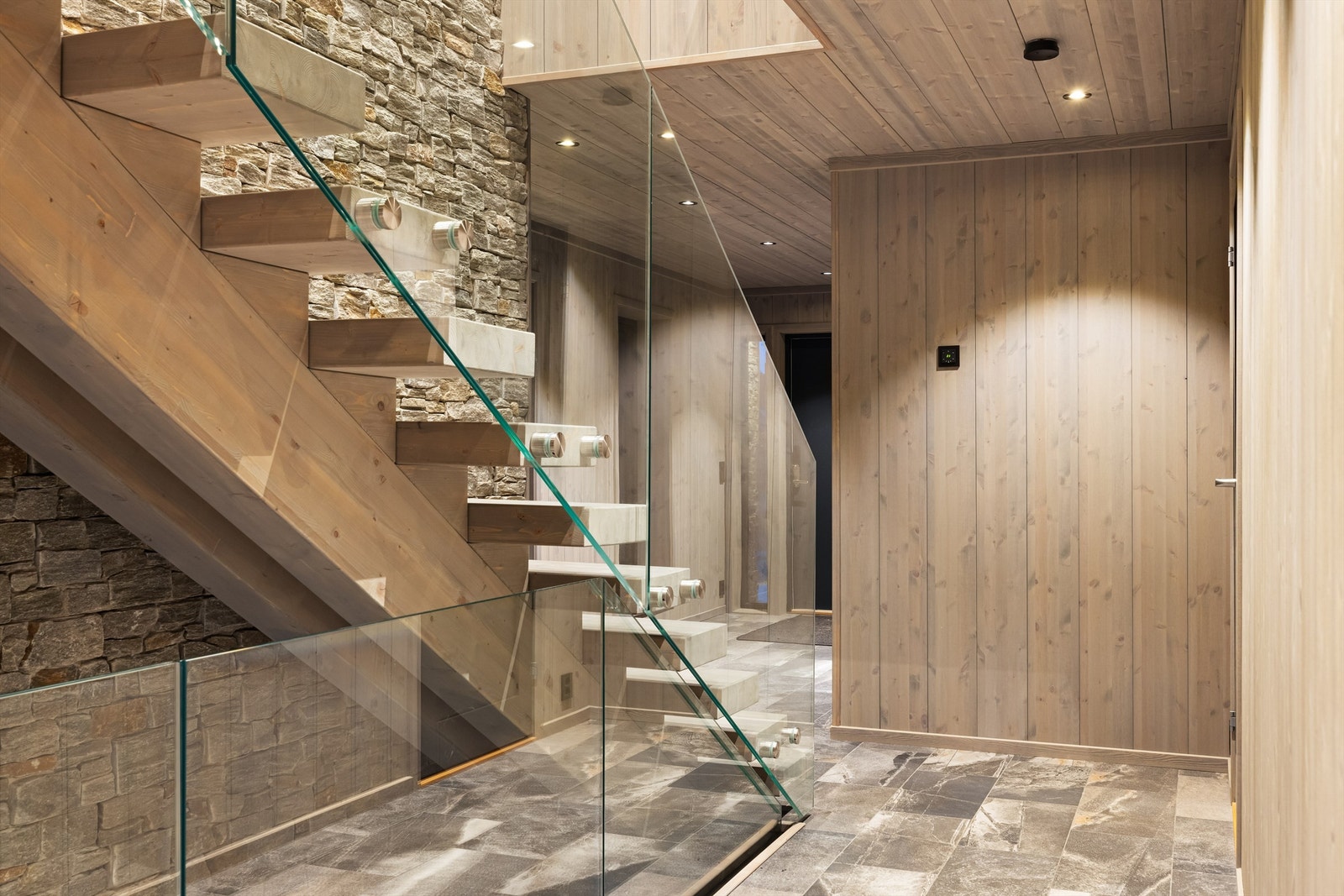 Stilfull plassbygd trapp i heltre. Glassrekkverk. Skiferforblendet vegg som strekker seg mellom etasjene. Galleribilde