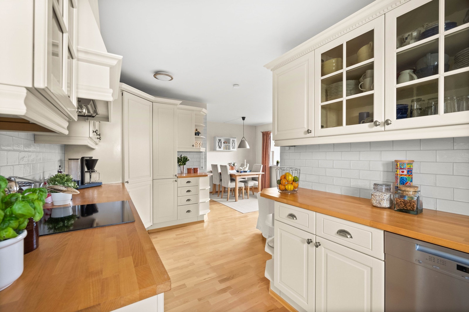 Oppvaskmaskin, komfyr, kokeplate og kjøleskap. Flislagt over benkeplate. Galleribilde