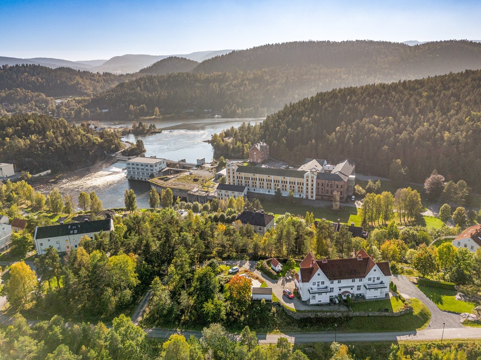 Dronefoto med "Gamle Skotfoss Bruk" og fossen i bakgrunnen. Fra eiendommen er det kort vei til Løveid sluser og til Norsjø hvor det er fine muligheter for båtliv og bading. Galleribilde
