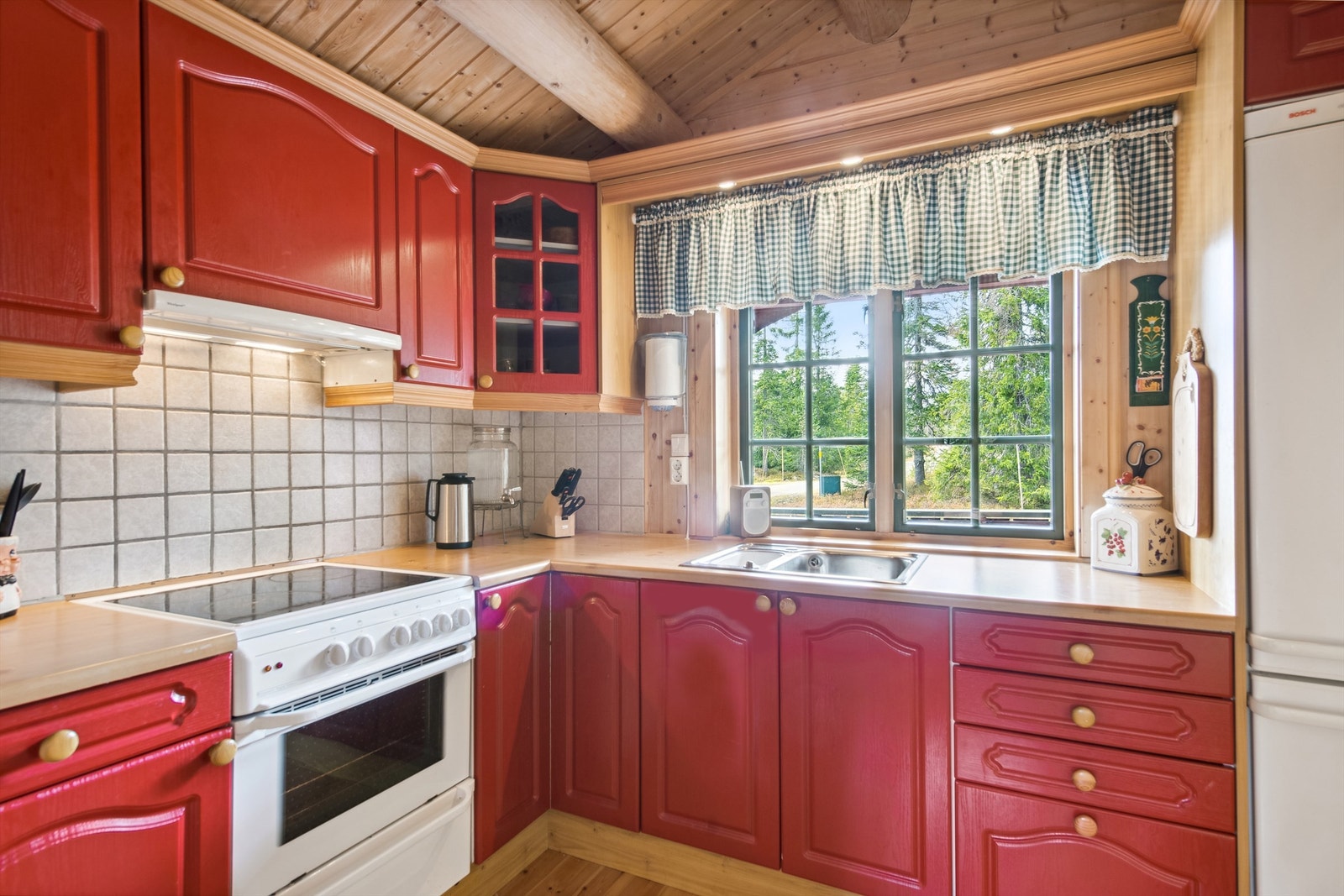 Pen kjøkkeninnredning med varmrøde skapfronter - Fliser på vegg over benk Galleribilde