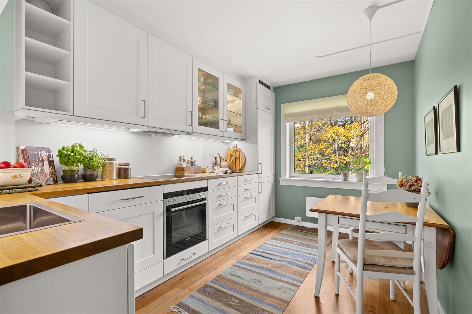 Separat og romslig kjøkken med integrerte hvitevarer og plass til spisegruppe Galleribilde