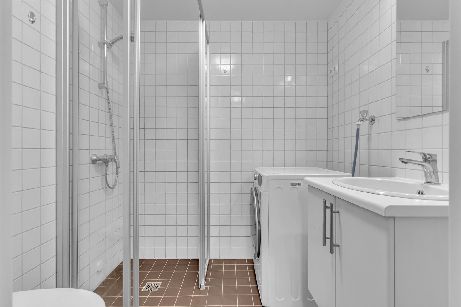 Baderomsinnredningen er bestående av servantskap med slette fronter og nedsenket servant i porselen med ett-greps armatur, speil, belysning og stikkontakter på vegg over servant, Dusjhjørne med skyvedører og to-greps armatur, vegghengt toalett med innebyg Galleribilde