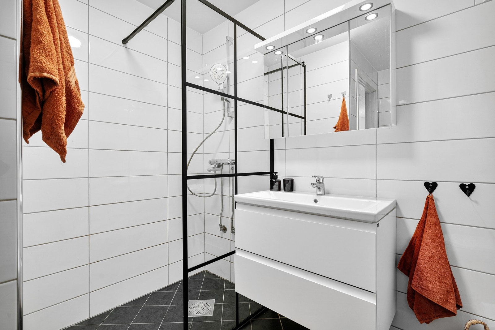 Lyst flislagt bad med svarte detaljer. Galleribilde