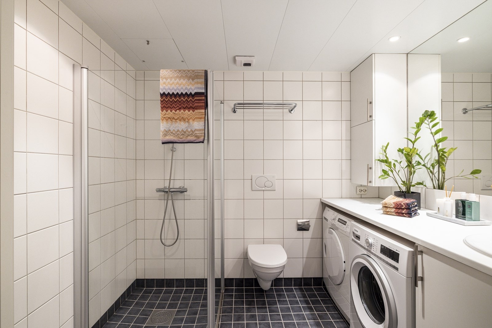 Pent flislagt bad med gulvvarme, downlights og opplegg til vaskemaskin og tørketrommel. Det er montert smart termostat på baderom Galleribilde