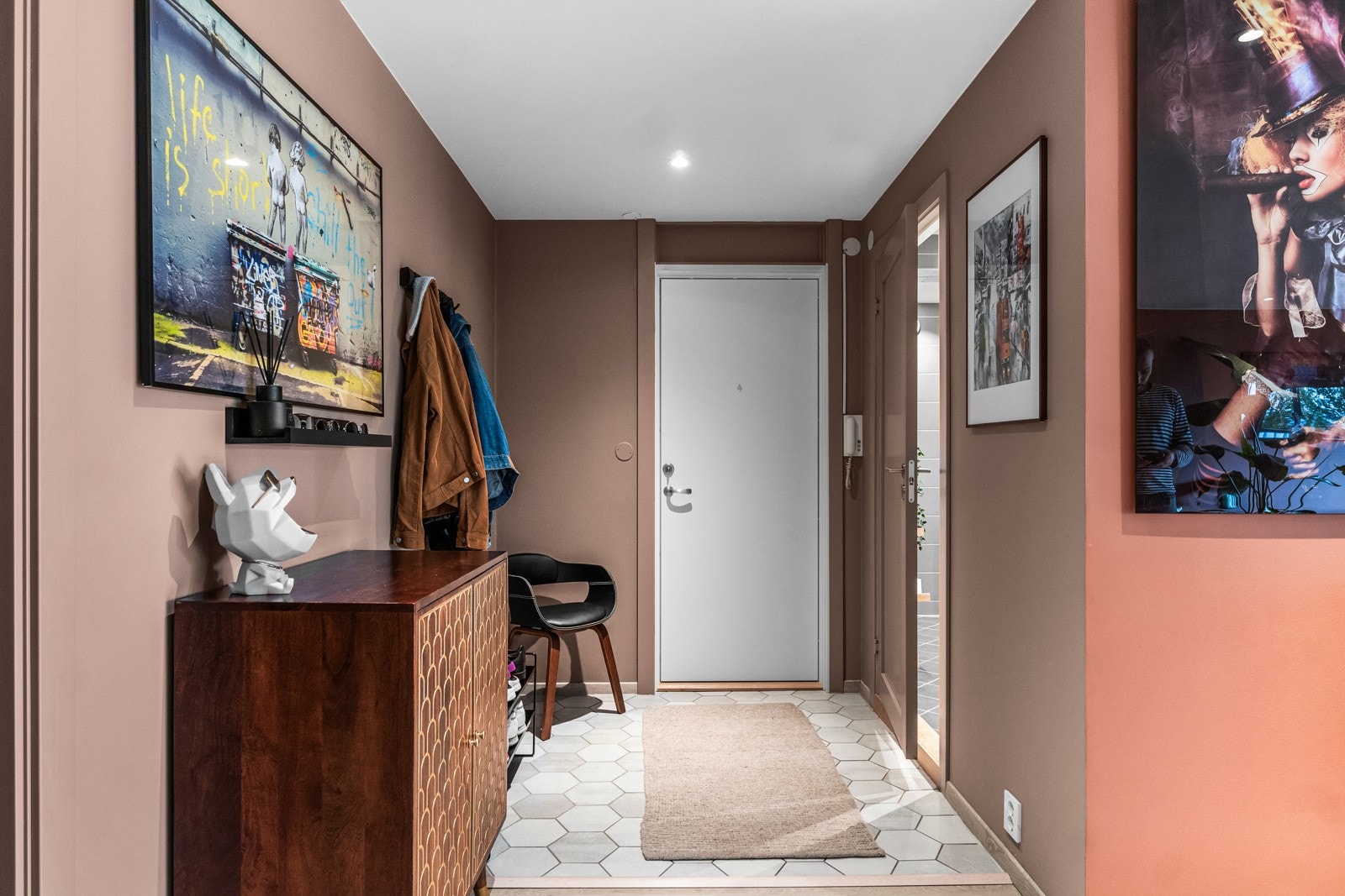 Velkommen inn til en innbydende entré med moderne uttrykk. Gulvet er belagt med lys laminat som står i fin kontrast til de varme rosa veggene, noe som skaper en lun atmosfære. Galleribilde