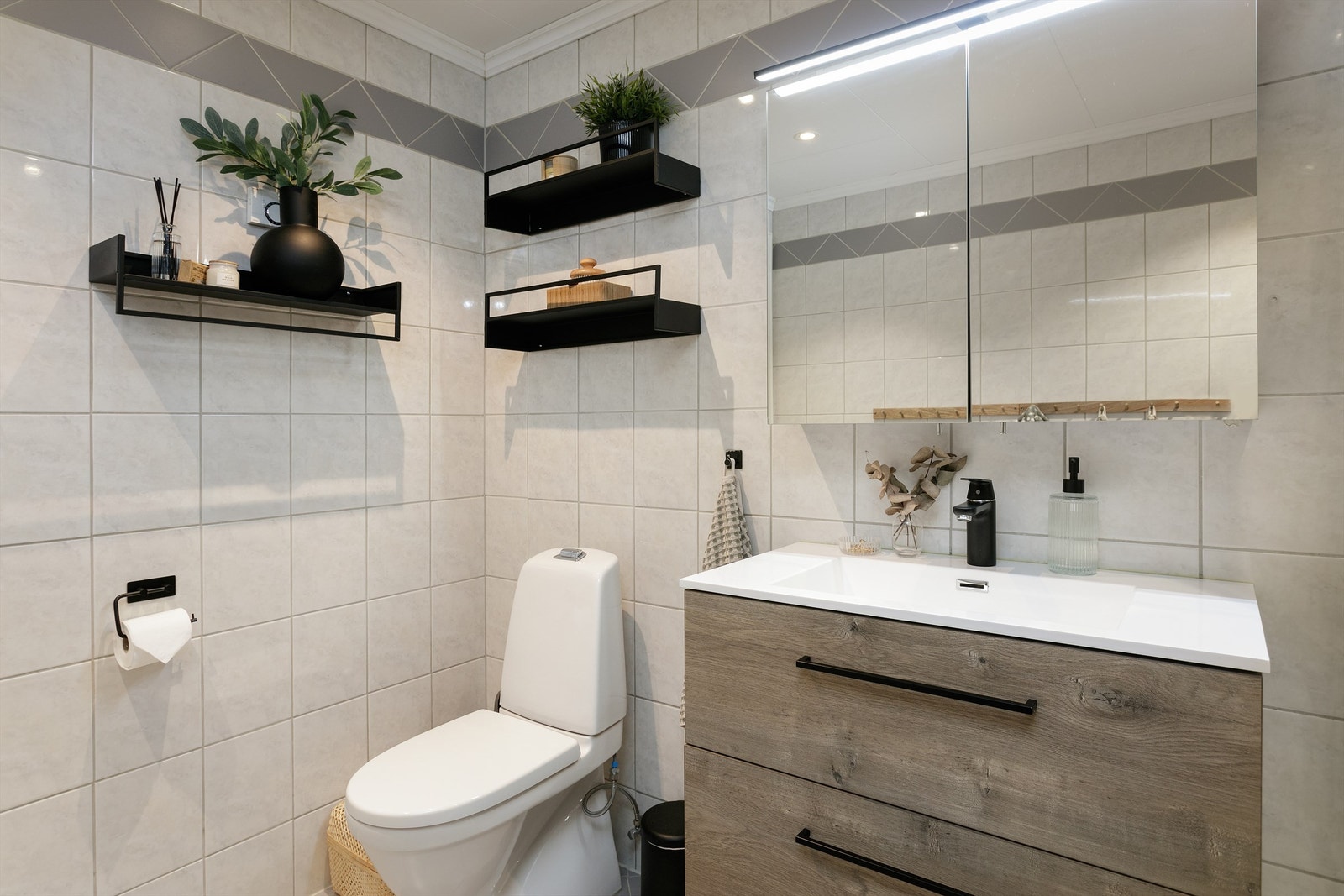 Baderomsinnredningen inkluderer et speilskap som gir gode oppbevaringsmuligheter sammen med dobbel skuffeseksjon i innredningen og høyskap i tilsvarende utseende Galleribilde