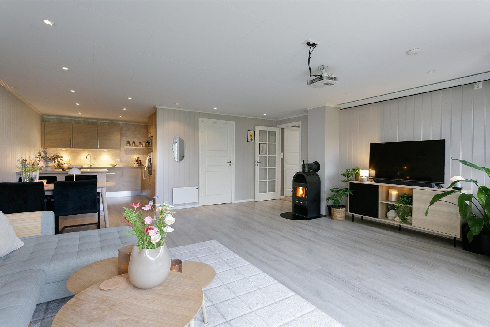 Fra gangen kommer man inn til det åpne stue-kjøkkenrommet. Det er lagt laminat på gulvflater i 2020. Veggene er malt i en mørk greige tone som gir rommet et moderne preg Galleribilde