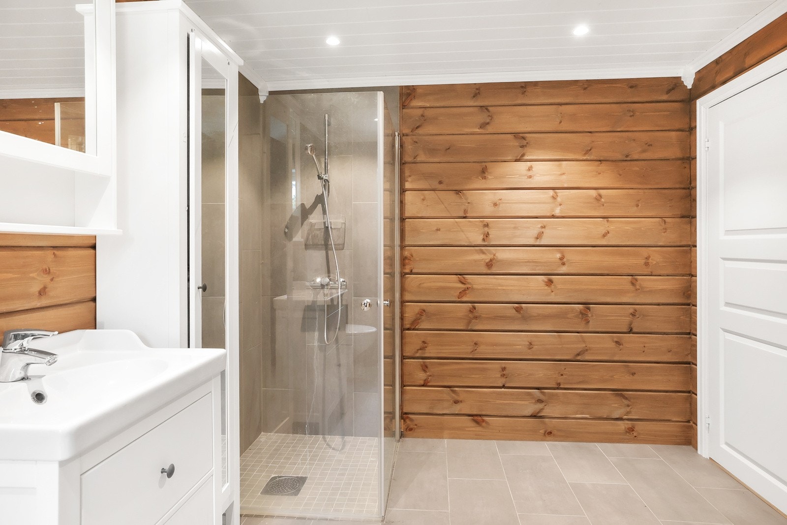 Badet har er en lys servantinnredning med plass til oppbevaring, toalett og dusjhjørne Galleribilde