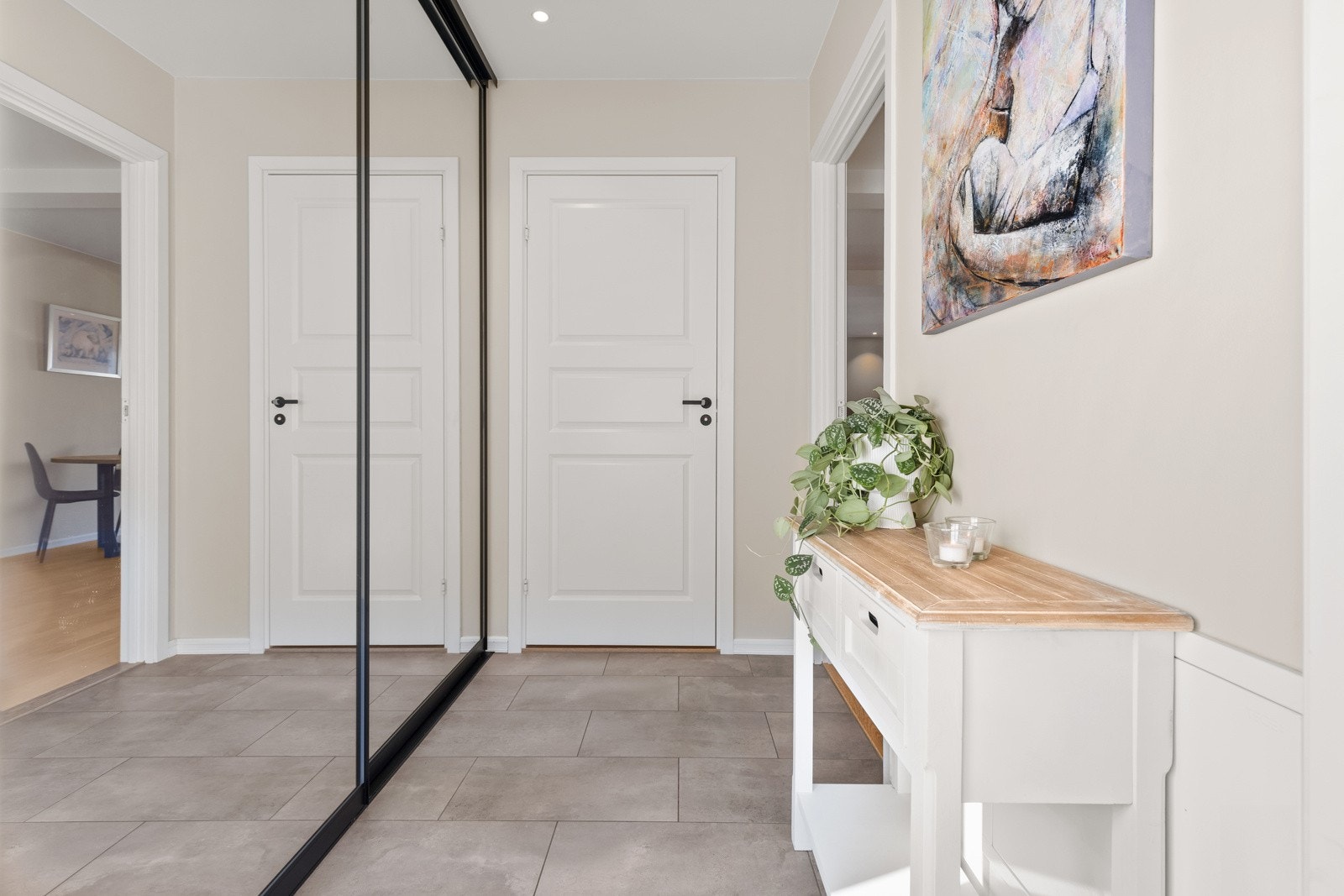 Lys og innbydende entrè med lysmalte veggflater og fliser på gulv, samt stor skyvedørsgarderobe med speilfronter. Himlingen er pent lyssatt med downlights. Galleribilde