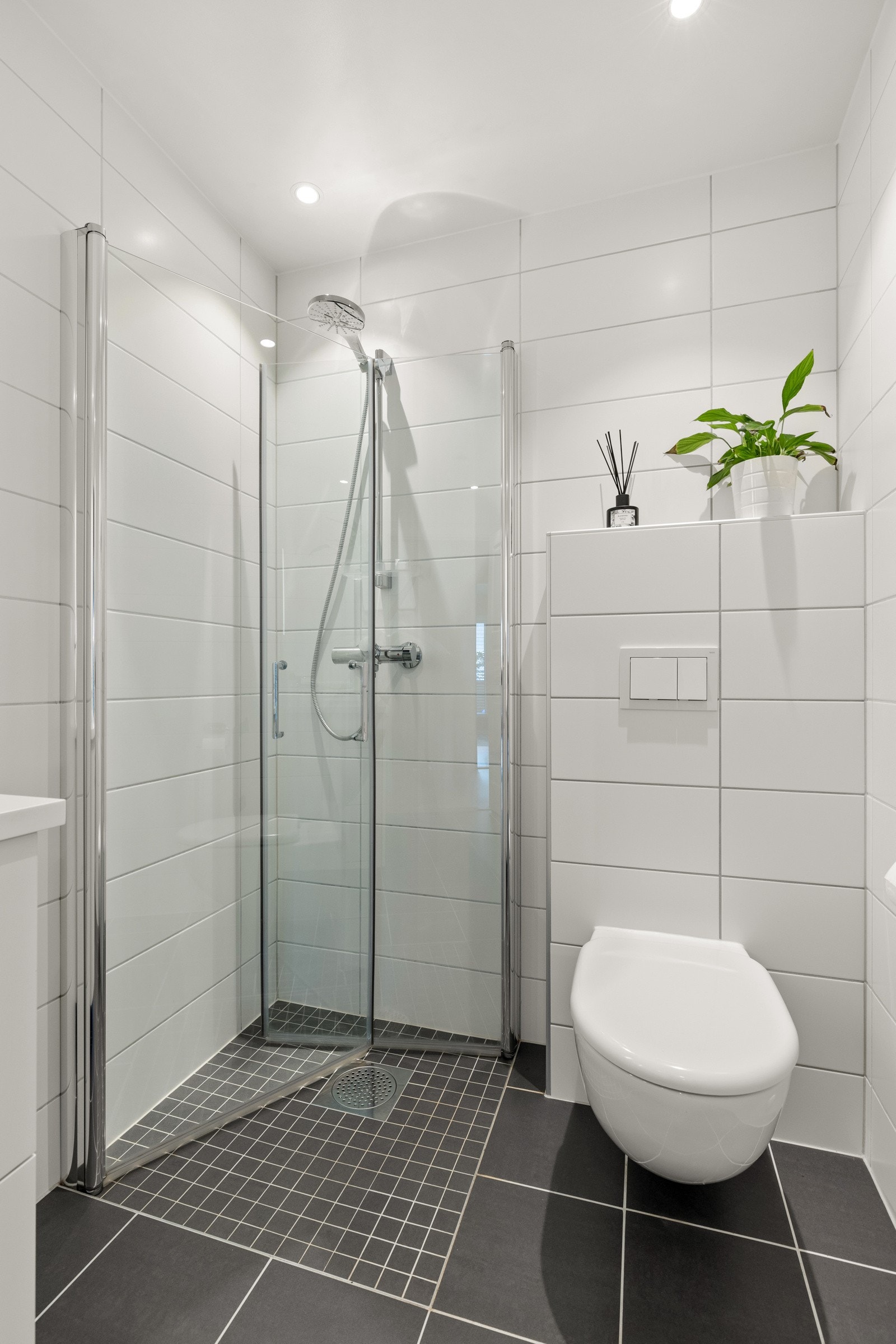 Videre har badet vegghengt toalett og dusjhjørne med innfellbare dører i herdet glass. Opplegg for vaskemaskin i tilknytning til innredning. Himlingen er lyssatt med downlights. Galleribilde
